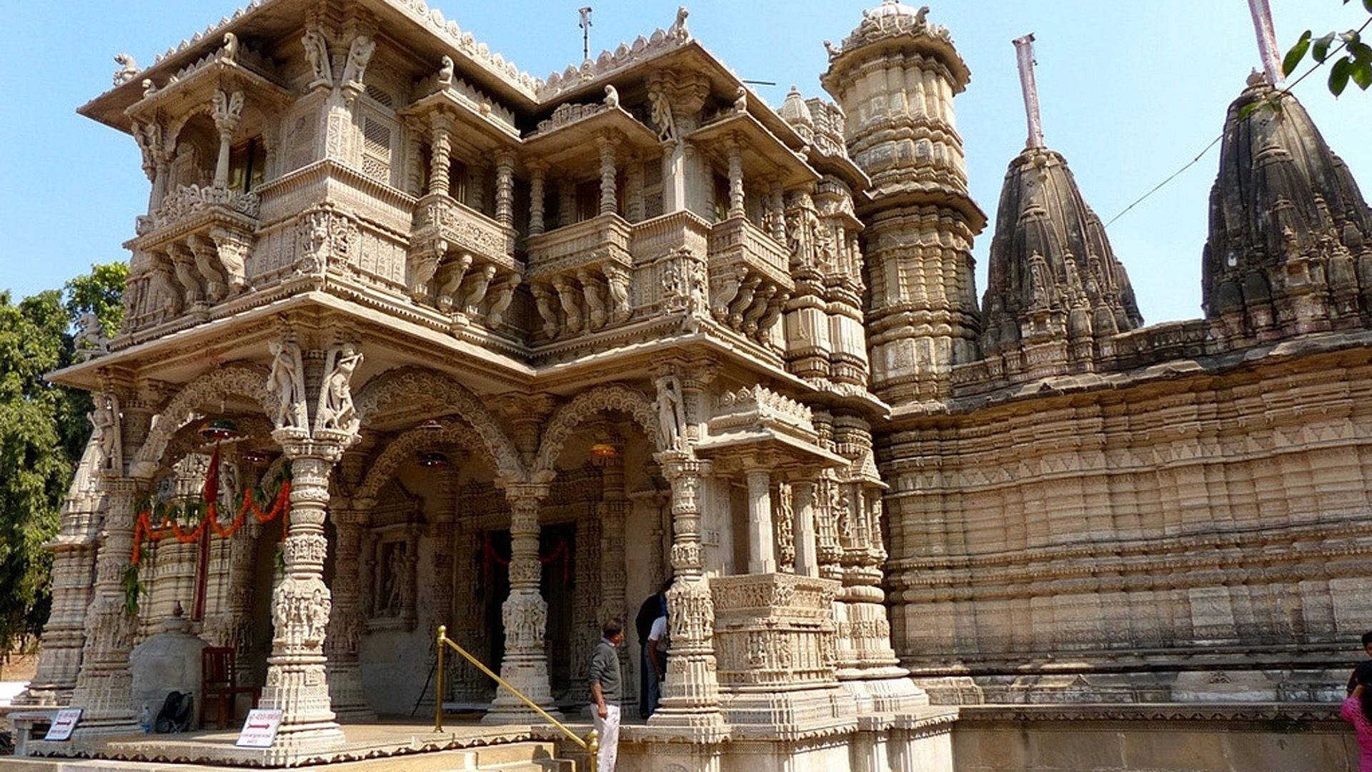 Ahmedabad 桌布 壁紙 — 在晴朗藍天下，一座雕刻精美的石廟，擁有華麗的柱子和圓頂。