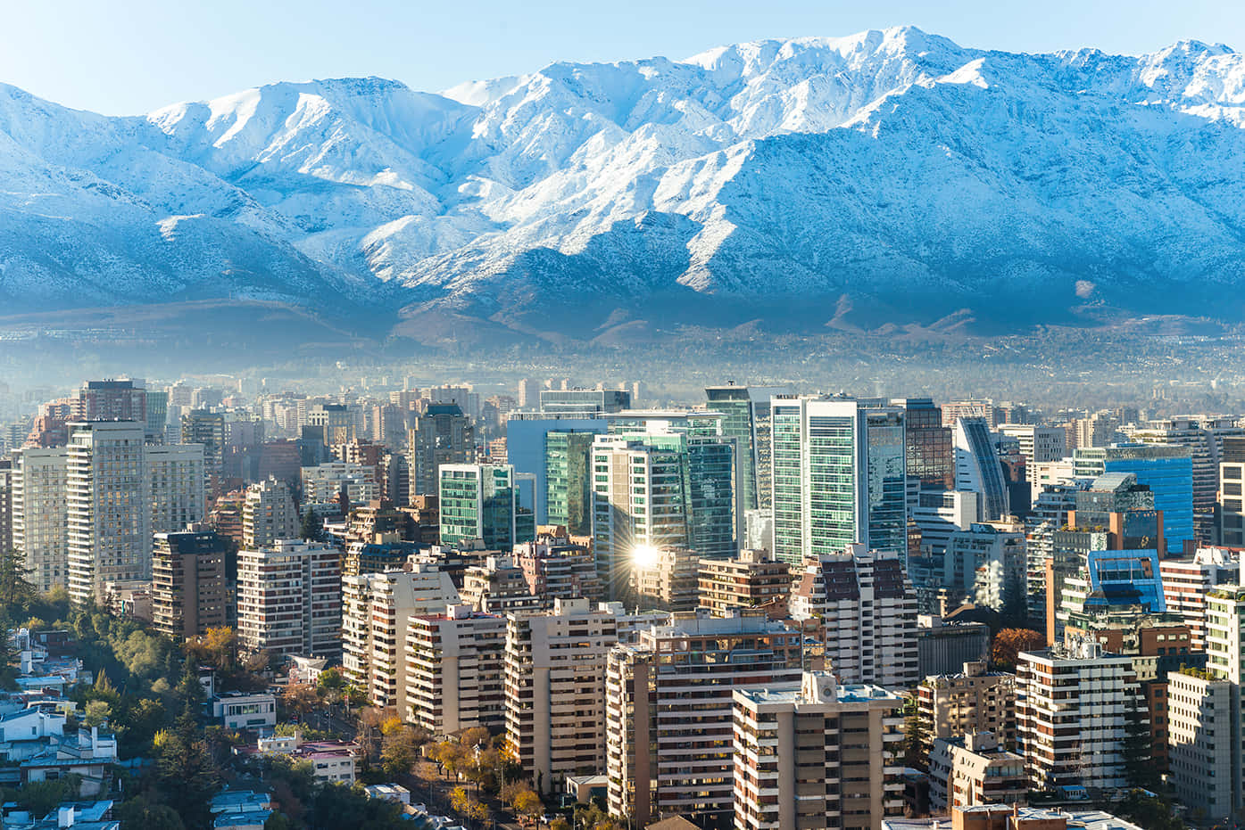 Beautiful City 桌布 壁紙 — 在晴朗藍天下，廣闊的城市景觀中，現代高樓大廈坐落在高聳的雪山腳下。