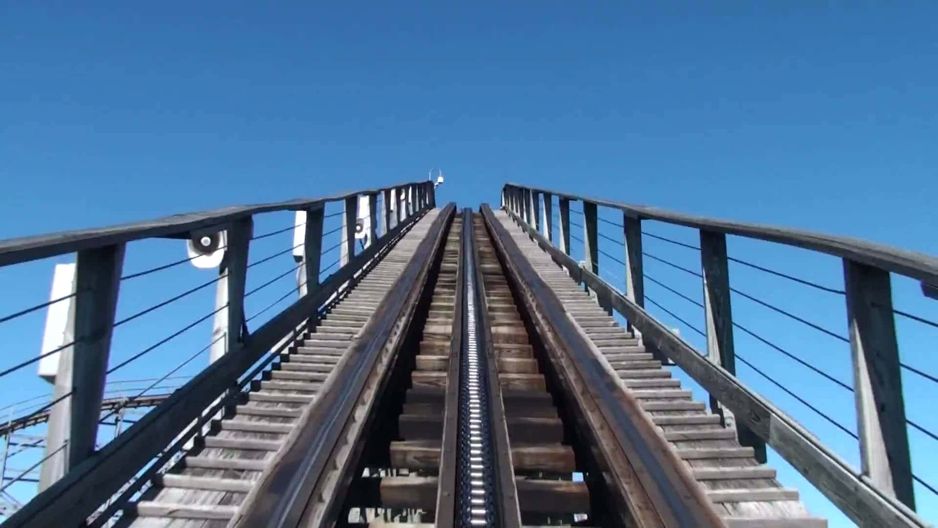 Roller Coaster 桌布 壁紙 — 在晴朗藍天下以第一人稱視角攀爬木製雲霄飛車軌道的刺激體驗。