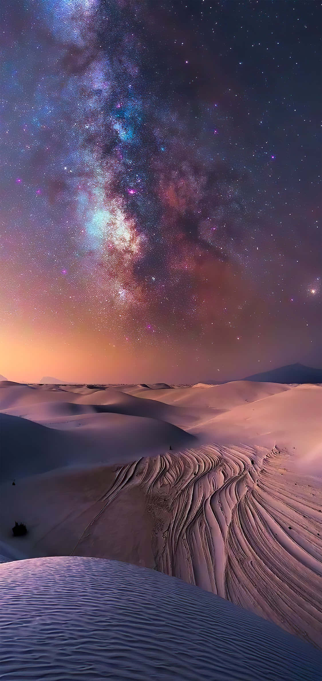 Desert iPhone 桌布 壁紙 — 在暮色天空下，廣闊沙漠中起伏的沙丘上，銀河系拱起的壯麗景觀。