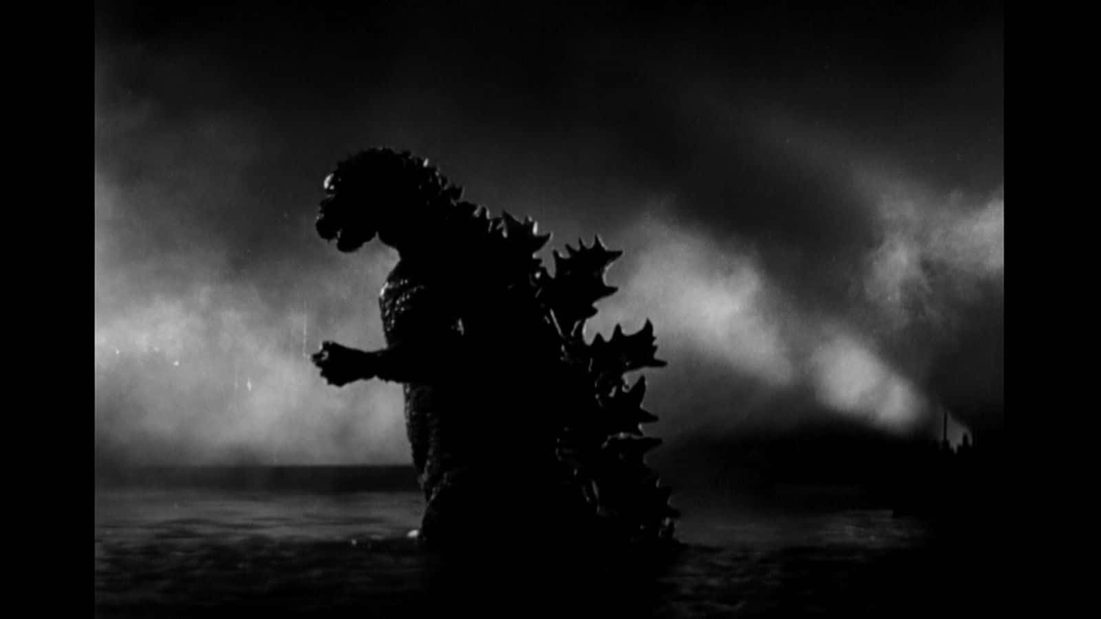 Godzilla 1954 桌布 壁紙 — 在暴風雨夜空的戲劇性背光下，高聳的哥吉拉剪影從水中浮現。