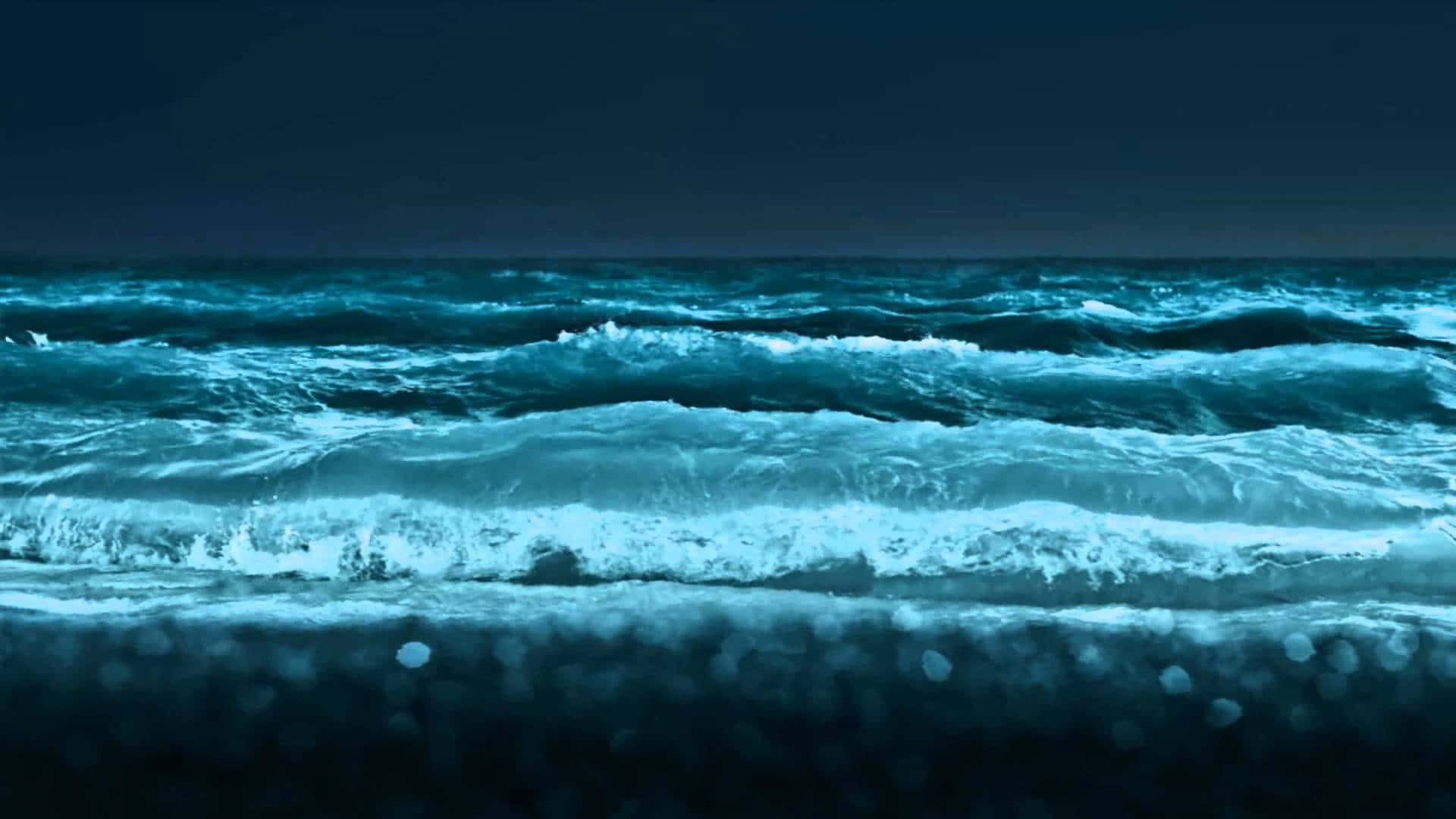 Ocean Waves 桌布 壁紙 — 在暴風雨的夜空下，強勁的藍綠色波浪衝擊著黑暗的海岸。