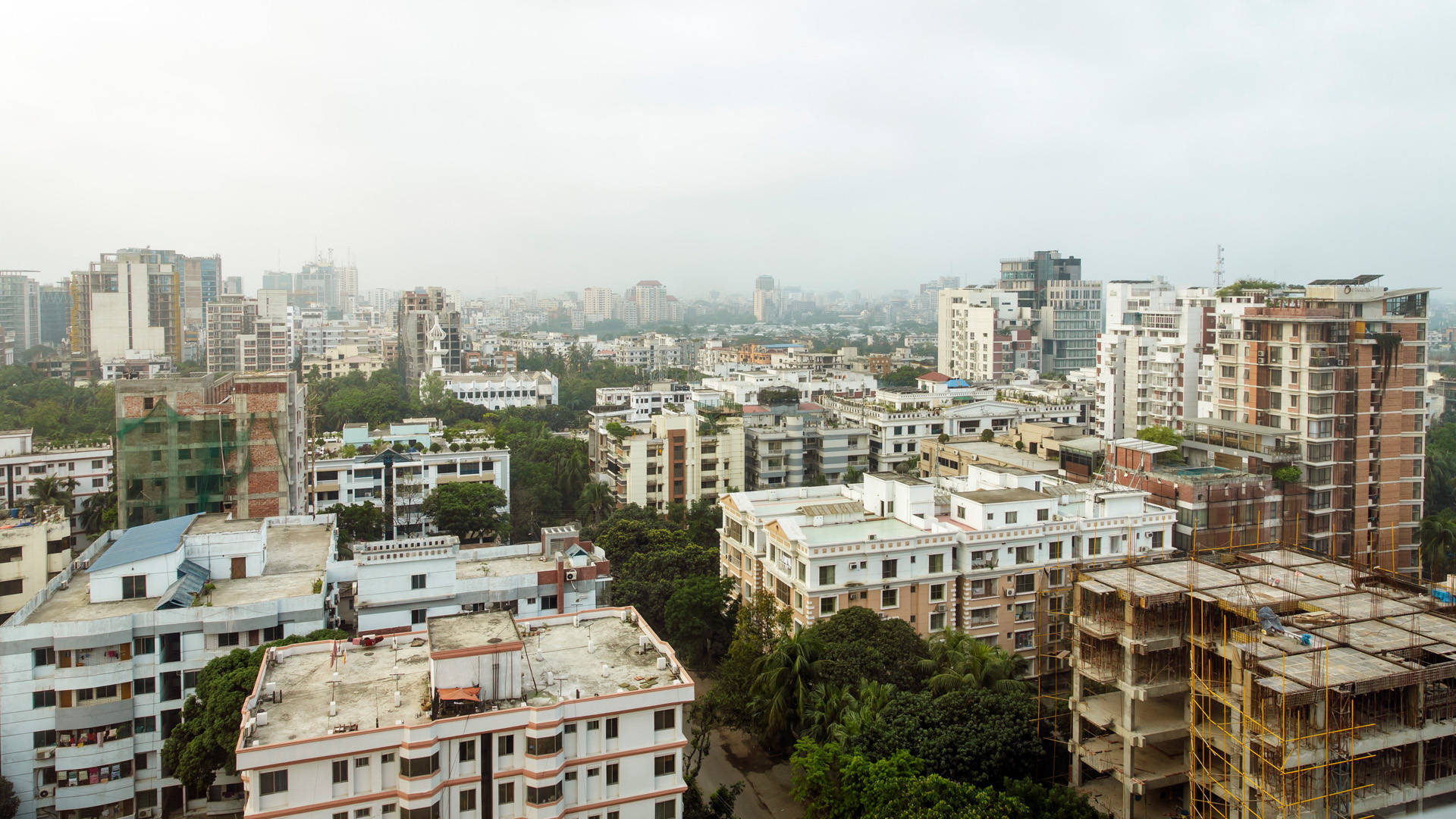 Bangladesh 桌布 壁紙 — 在朦朧多雲的天空下，高樓與低層建築混合的廣闊城市天際線。
