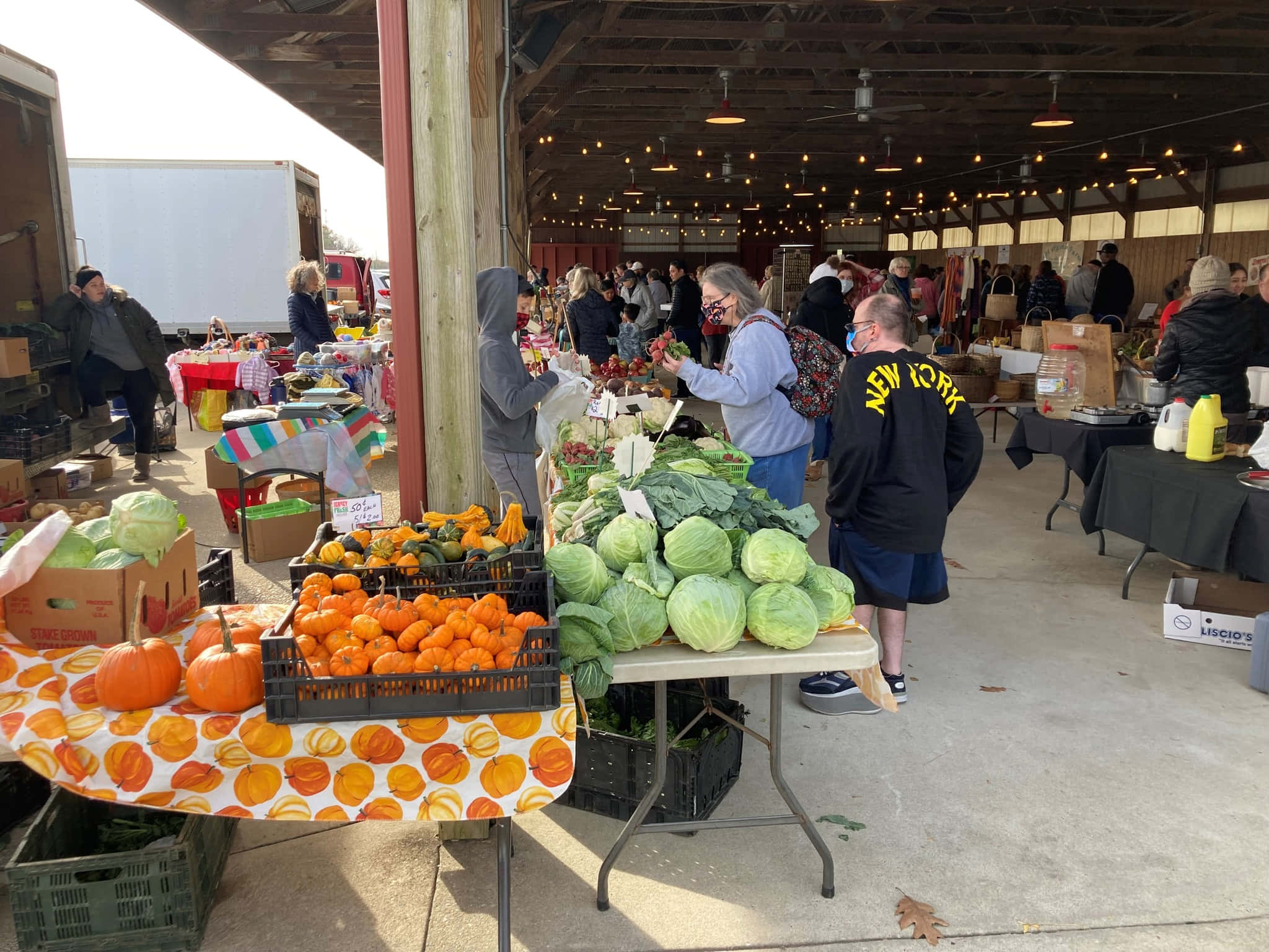 Farmers Market 桌布 壁紙 — 在木製涼亭下充滿活力的秋季農貿市場，有南瓜、高麗菜和購物者瀏覽新鮮農產品。