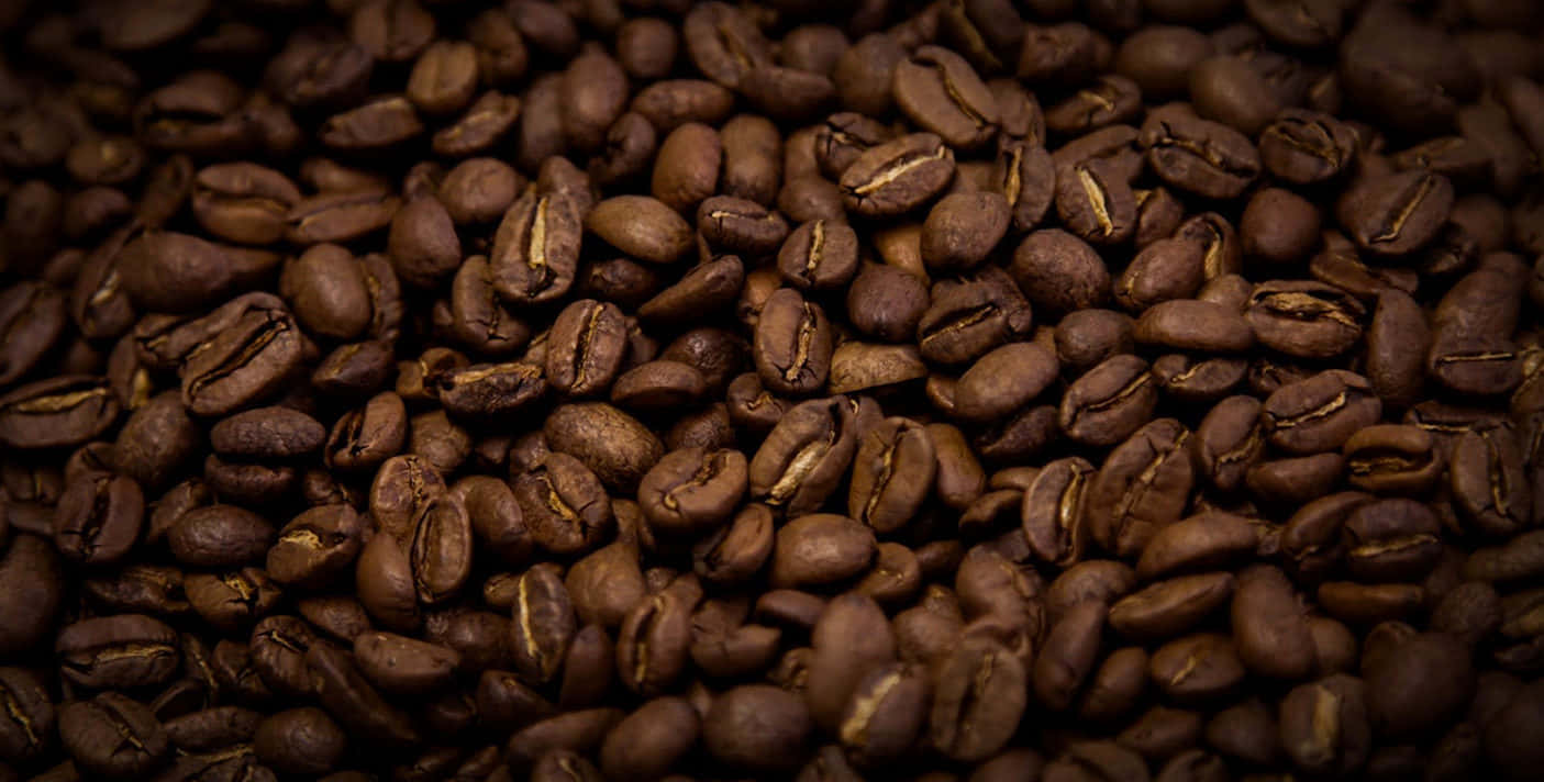Brown Coffee 桌布 壁紙 — 在柔和光線下，深度烘焙咖啡豆的特寫，呈現深棕色色調和可見的皺紋。