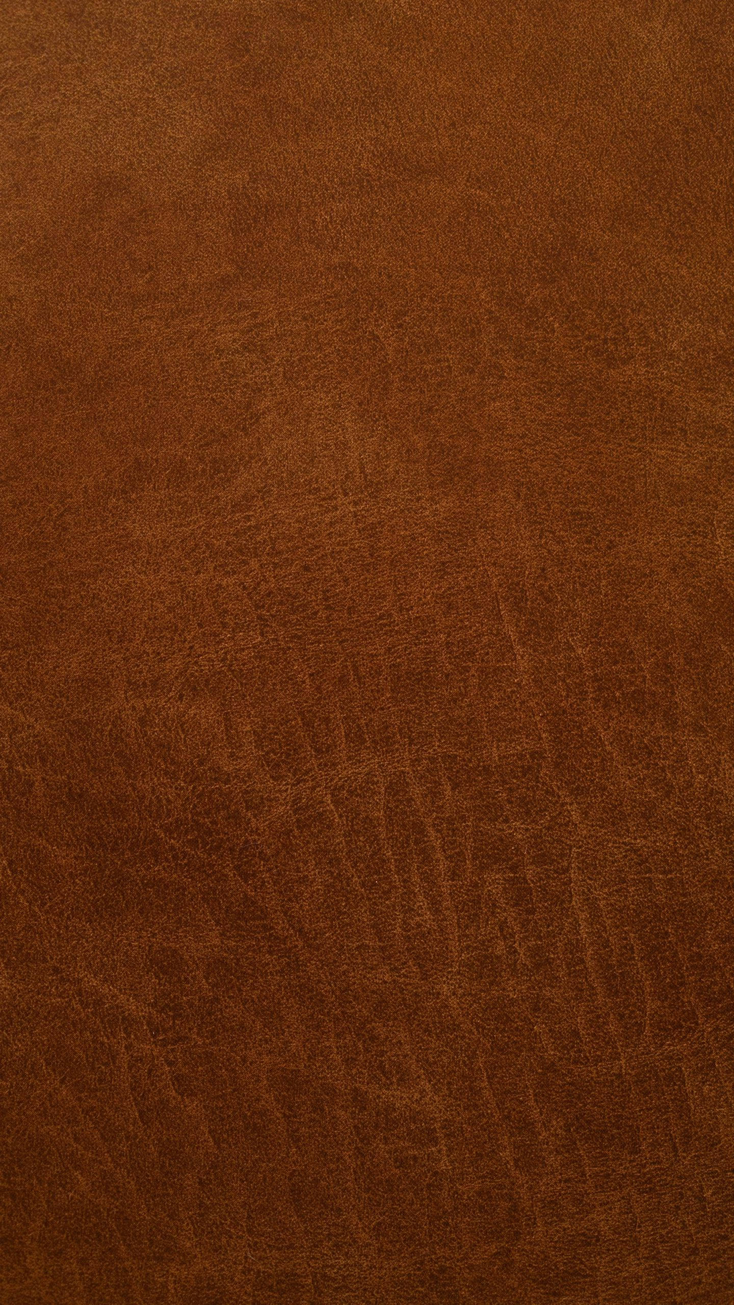 Brown iPhone 桌布 壁紙 — 在柔和光線下，豐富棕色皮革的特寫，展現自然紋理和細微皺褶。