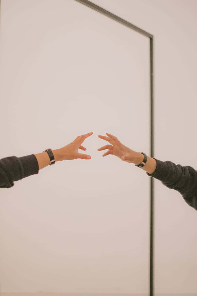 reflection 桌布 壁紙 — 在柔和光線的簡約房間中，兩隻手穿過鏡子的反射互相伸向對方。