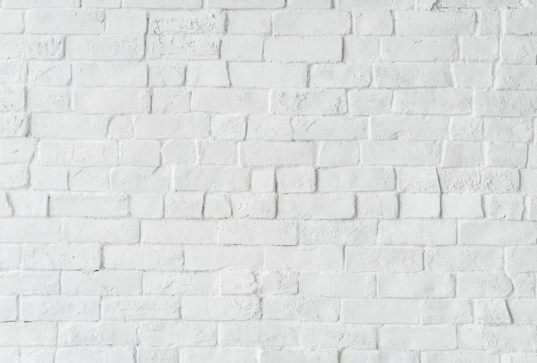 White Brick 桌布 壁紙 — 在柔和均勻的燈光下，一面乾淨的白色磚牆，帶有細微紋理和砂漿線。