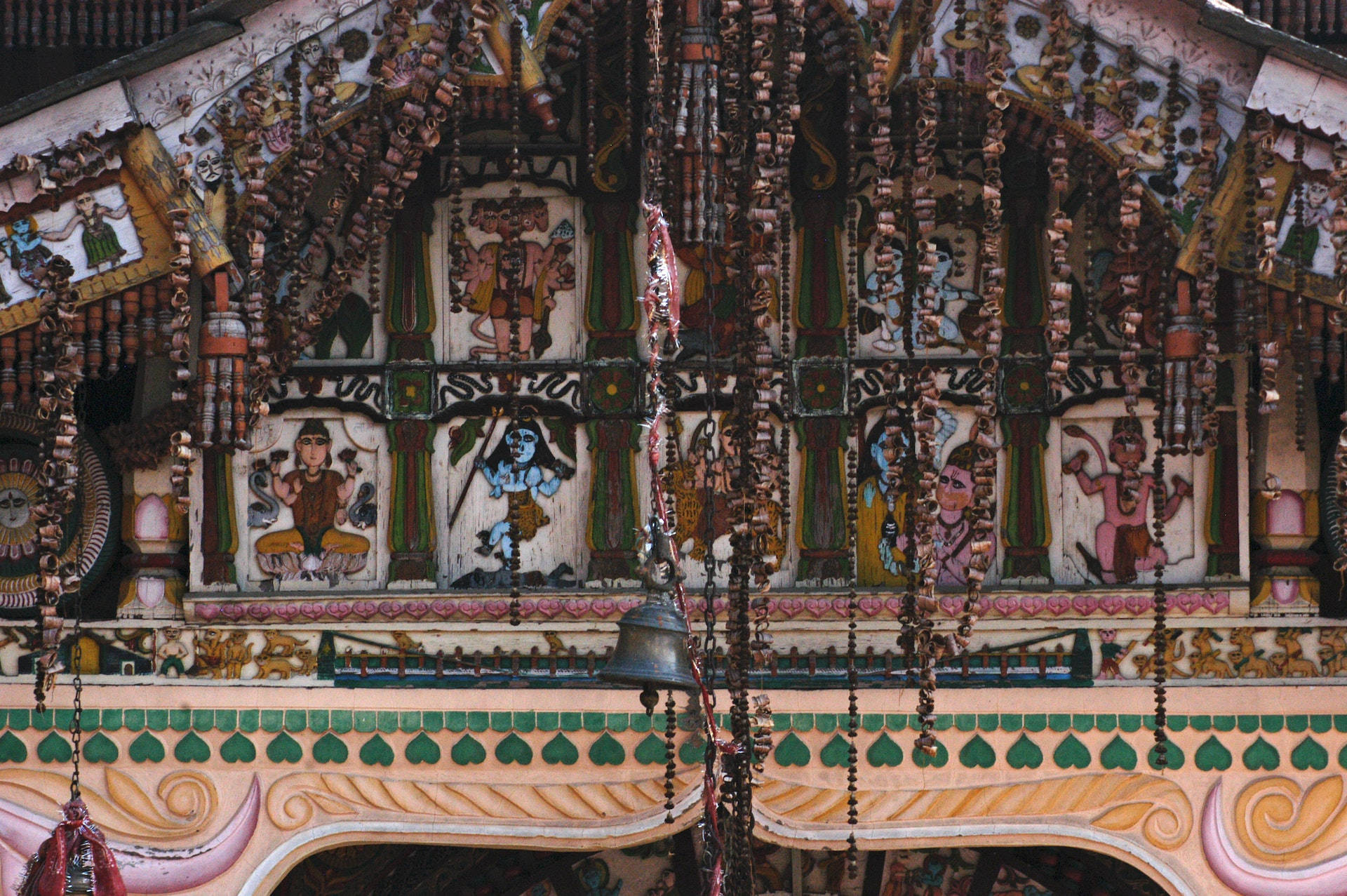 Hindu Temple 桌布 壁紙 — 在柔和日光下，一座充滿活力的華麗寺廟外牆，裝飾著色彩繽紛的彩繪神祇和懸掛的珠簾。