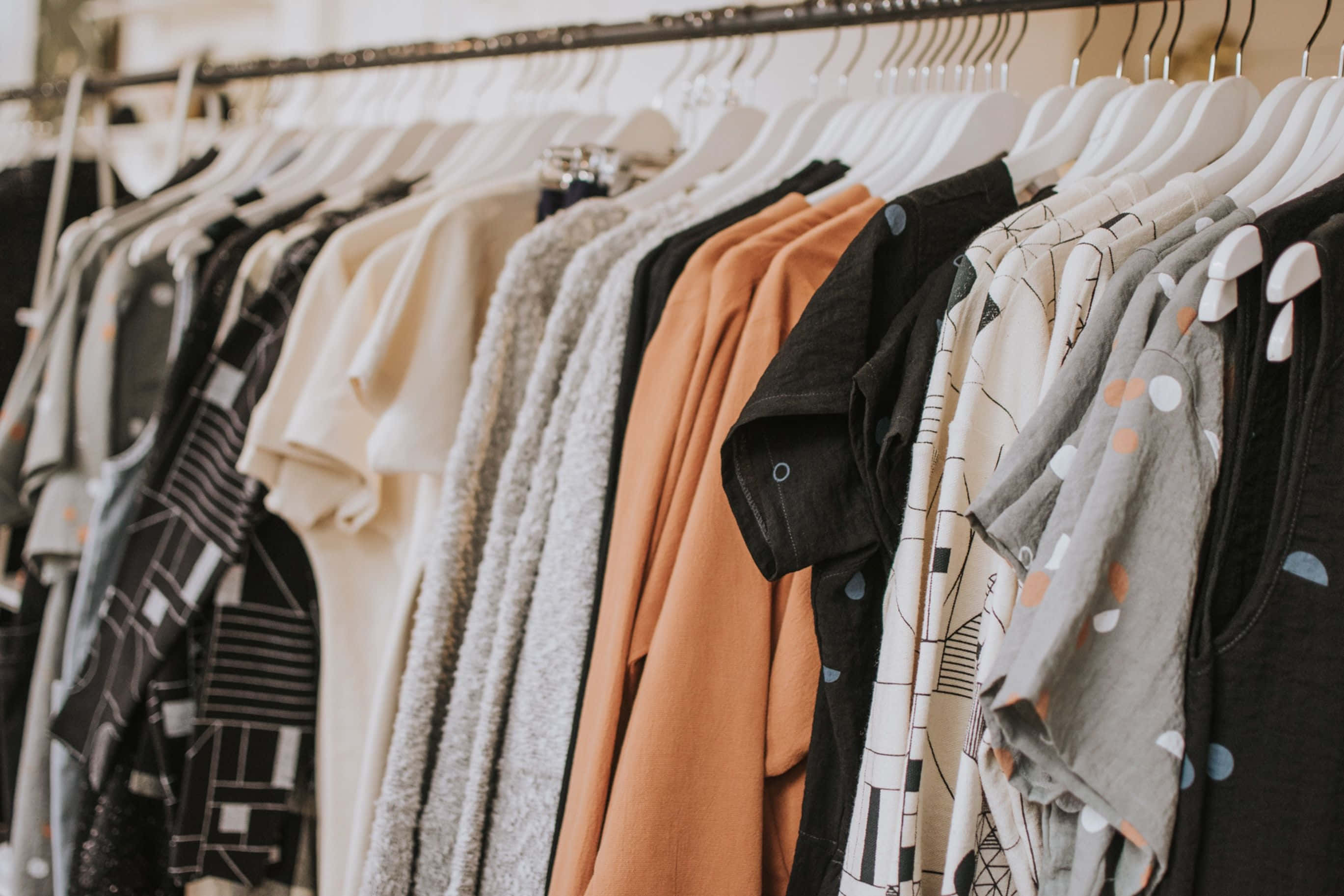 Clothes 桌布 壁紙 — 在柔和燈光的服裝店中，整齊排列在白色衣架上的T恤特寫。