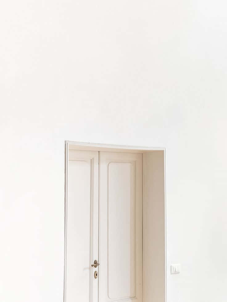Minimalist Photography 桌布 壁紙 — 在柔和環境光下，簡約白色牆壁上設置的帶有黃銅手柄的白色門。