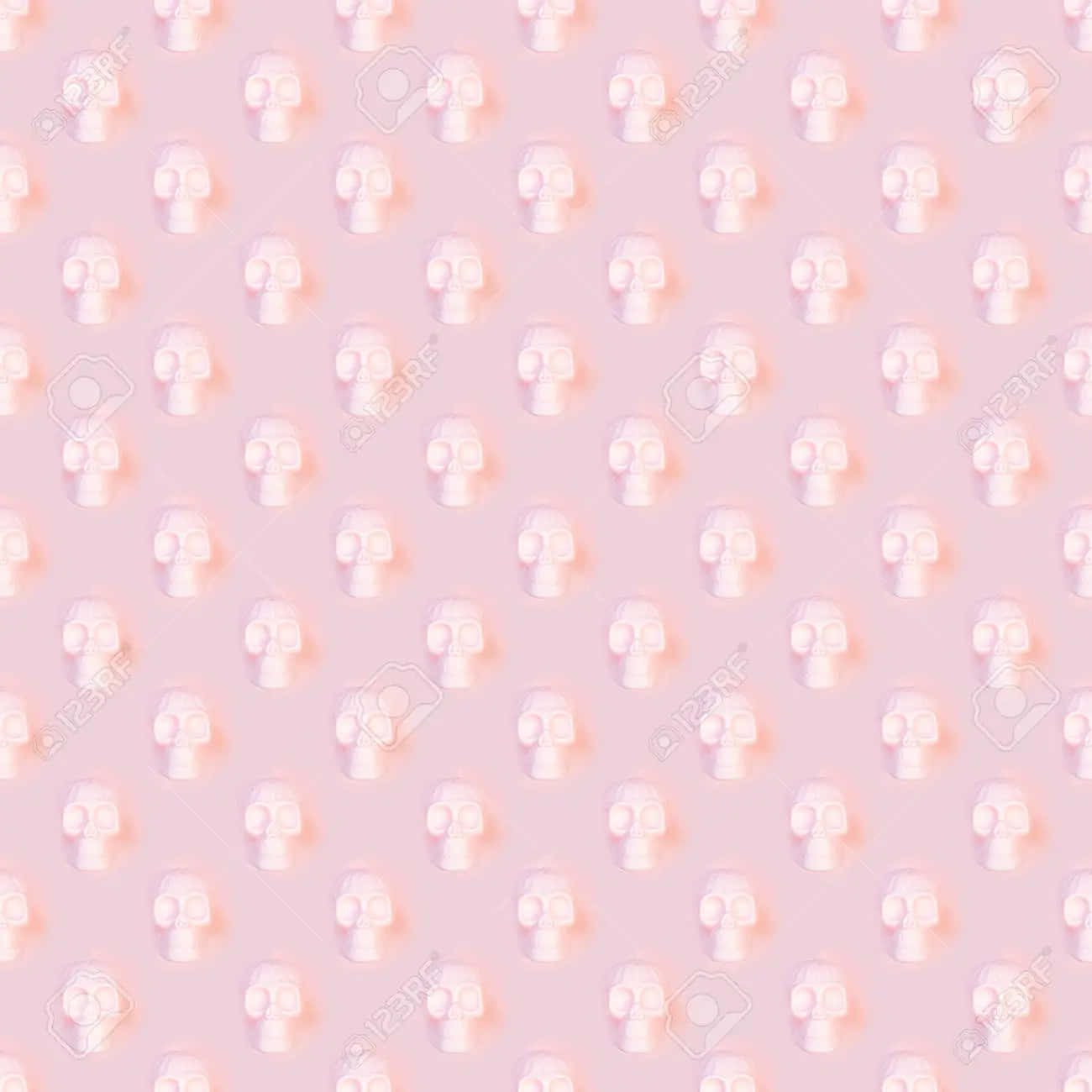 Pastel Halloween 桌布 壁紙 — 在柔和的粉紅色背景上，帶有微妙陰影效果的發光白色骷髏圖示重複圖案。
