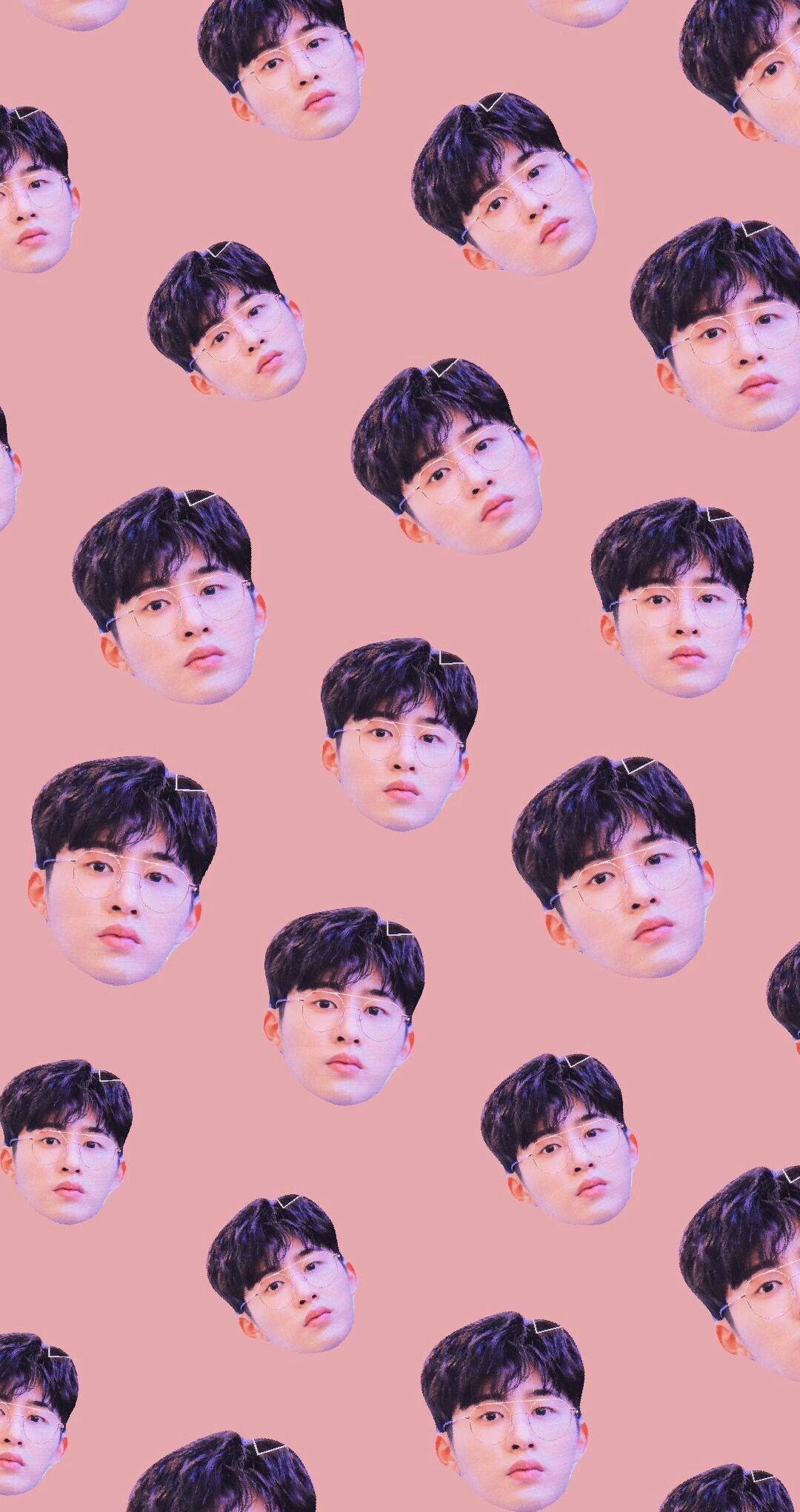 kim hanbin 桌布 壁紙 — 在柔和的粉紅色背景上重複出現的年輕男子面孔圖案，深色頭髮，戴眼鏡。