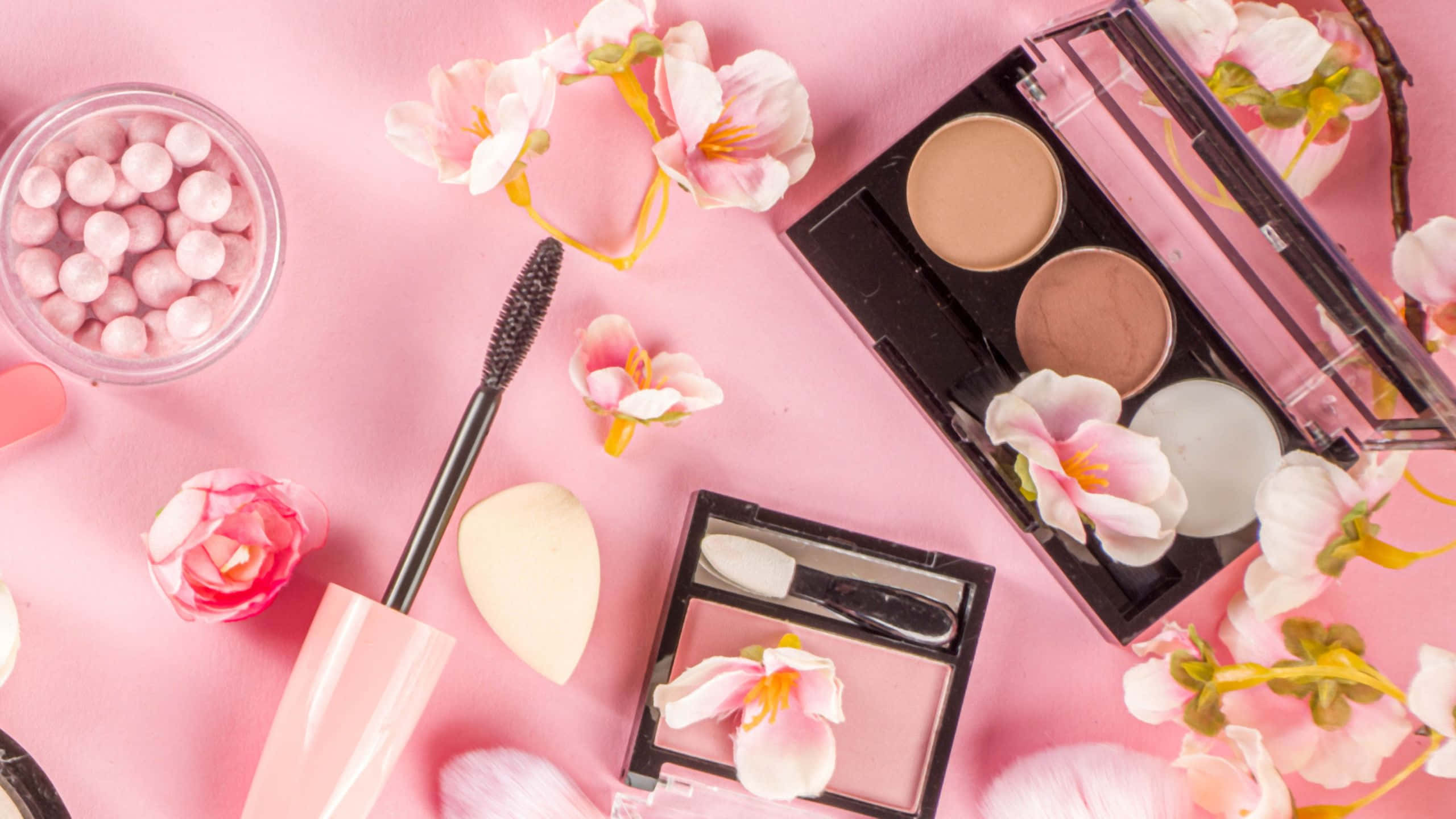 Makeup 桌布 壁紙 — 在柔和粉紅色背景上，粉紅色美容產品和櫻花的平鋪佈置。