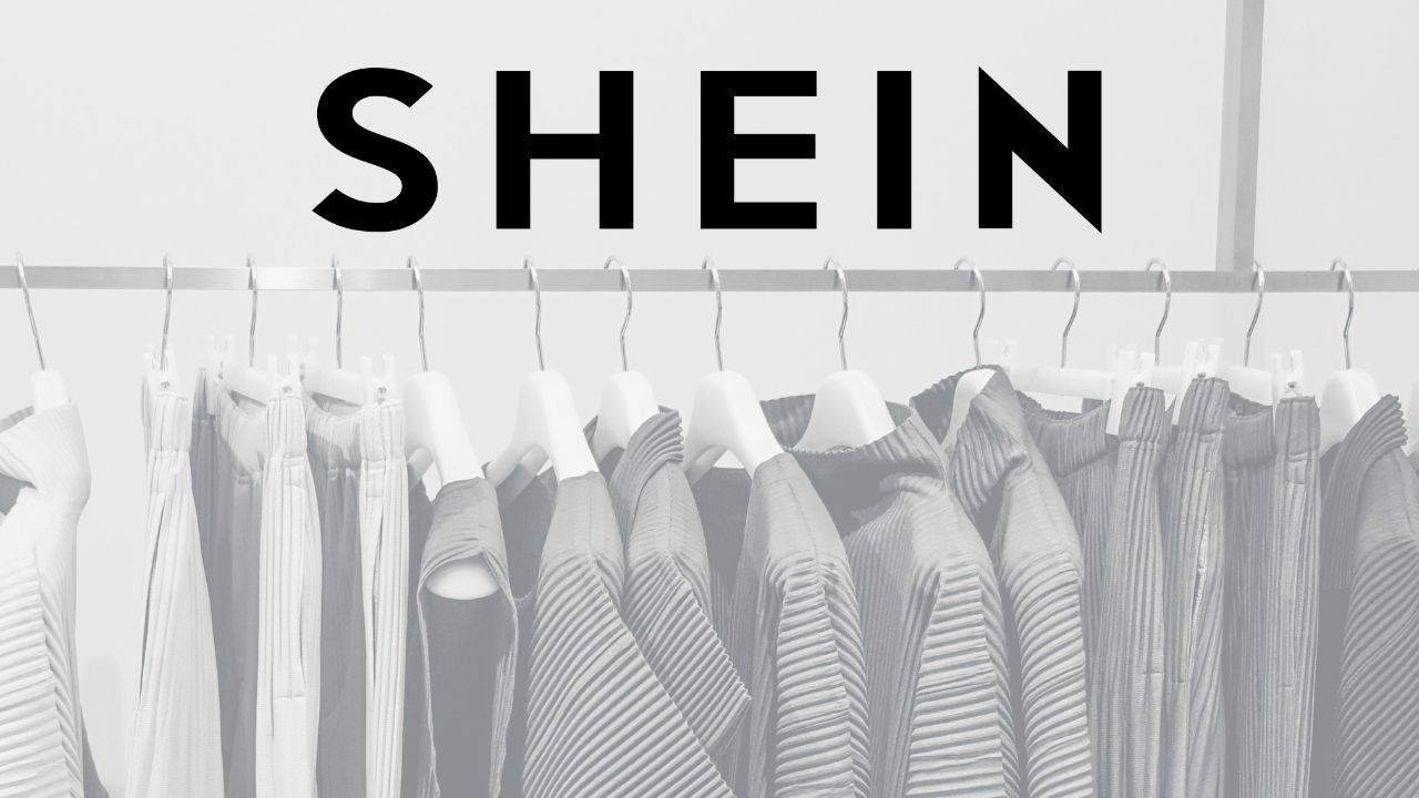 Shein 桌布 壁紙 — 在極簡零售環境中，帶有粗體SHEIN標誌的單色百褶衣物架。