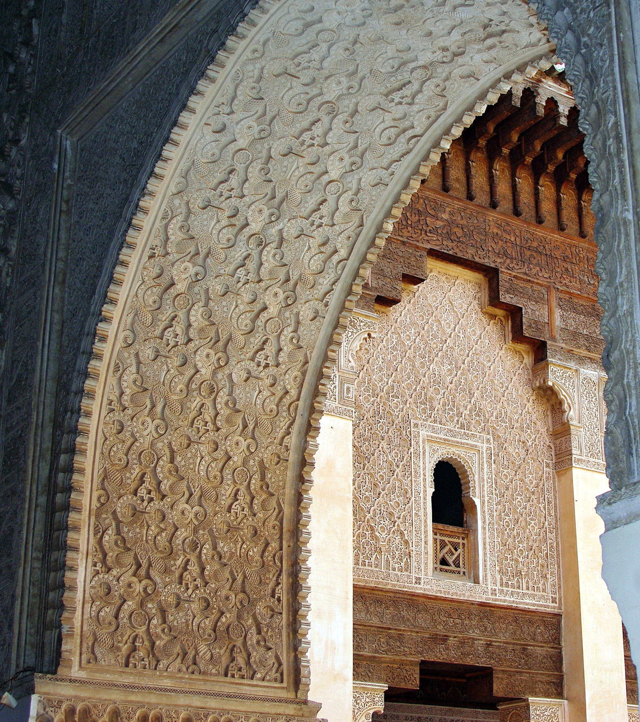 Morocco 桌布 壁紙 — 在歷史伊斯蘭建築結構中，一個雕刻精美的石拱門，帶有漩渦狀幾何圖案和一個小拱形窗戶。
