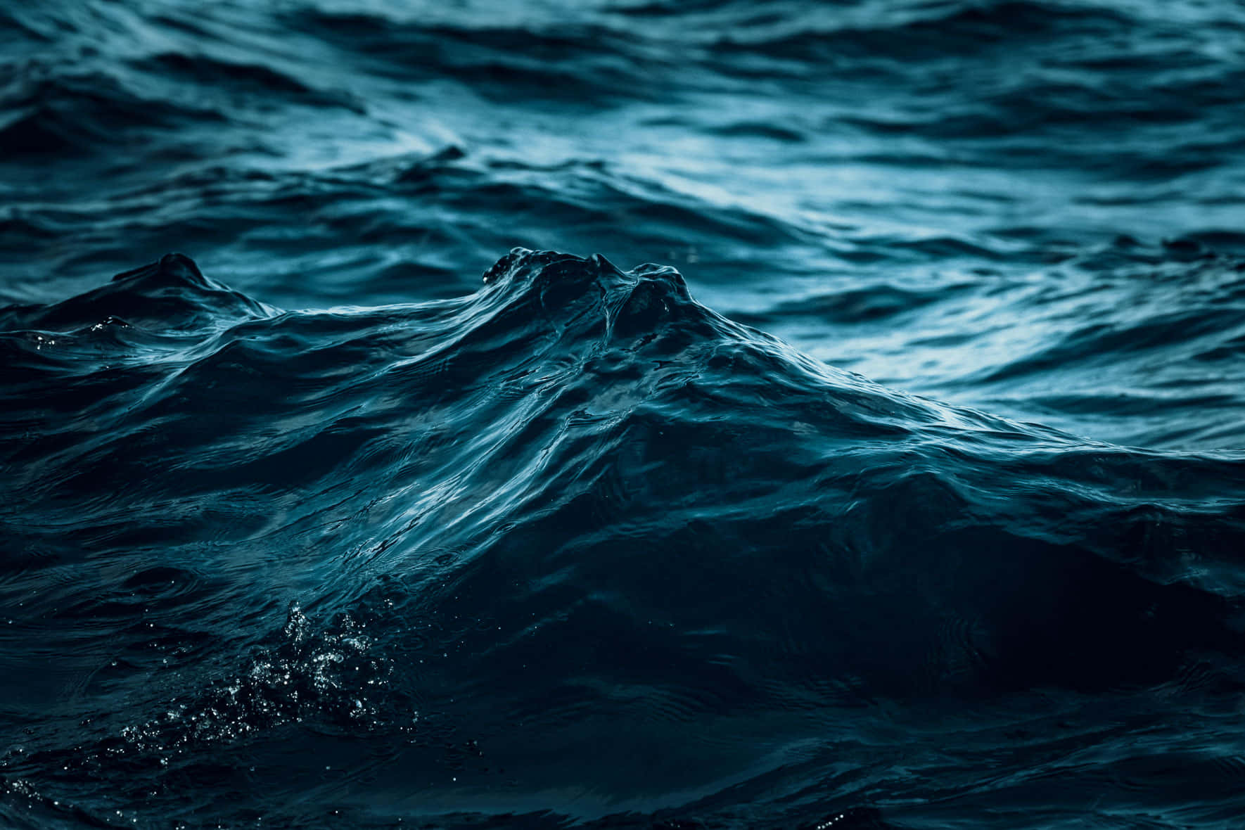 Ocean Water 桌布 壁紙 — 在氣氛燈光下，洶湧的深藍色海浪翻騰並帶有紋理泡沫的特寫。