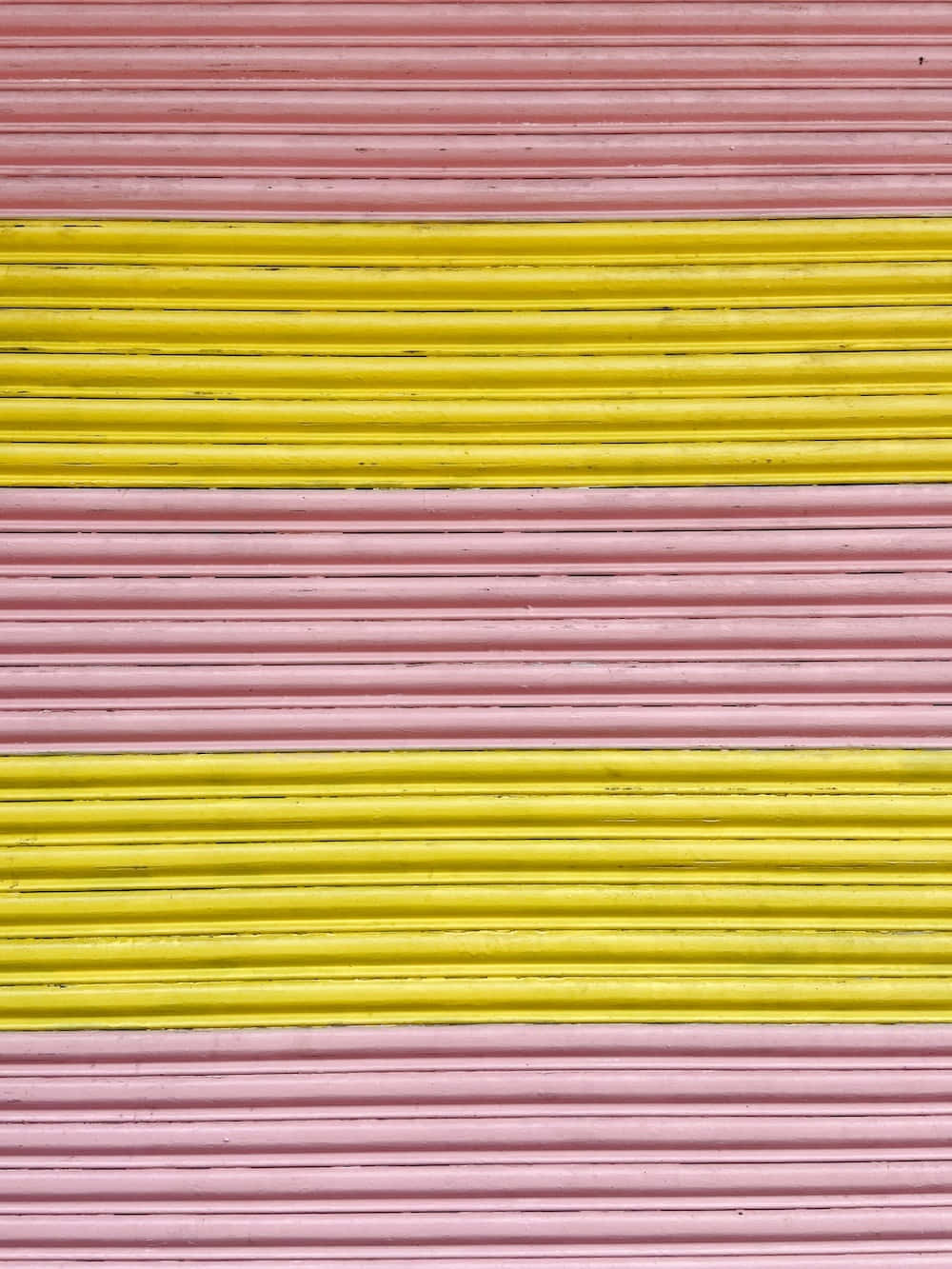 Pink And Yellow 桌布 壁紙 — 在波紋金屬表面上，大膽的粉紅色和黃色水平條紋創造出充滿活力的幾何圖案。