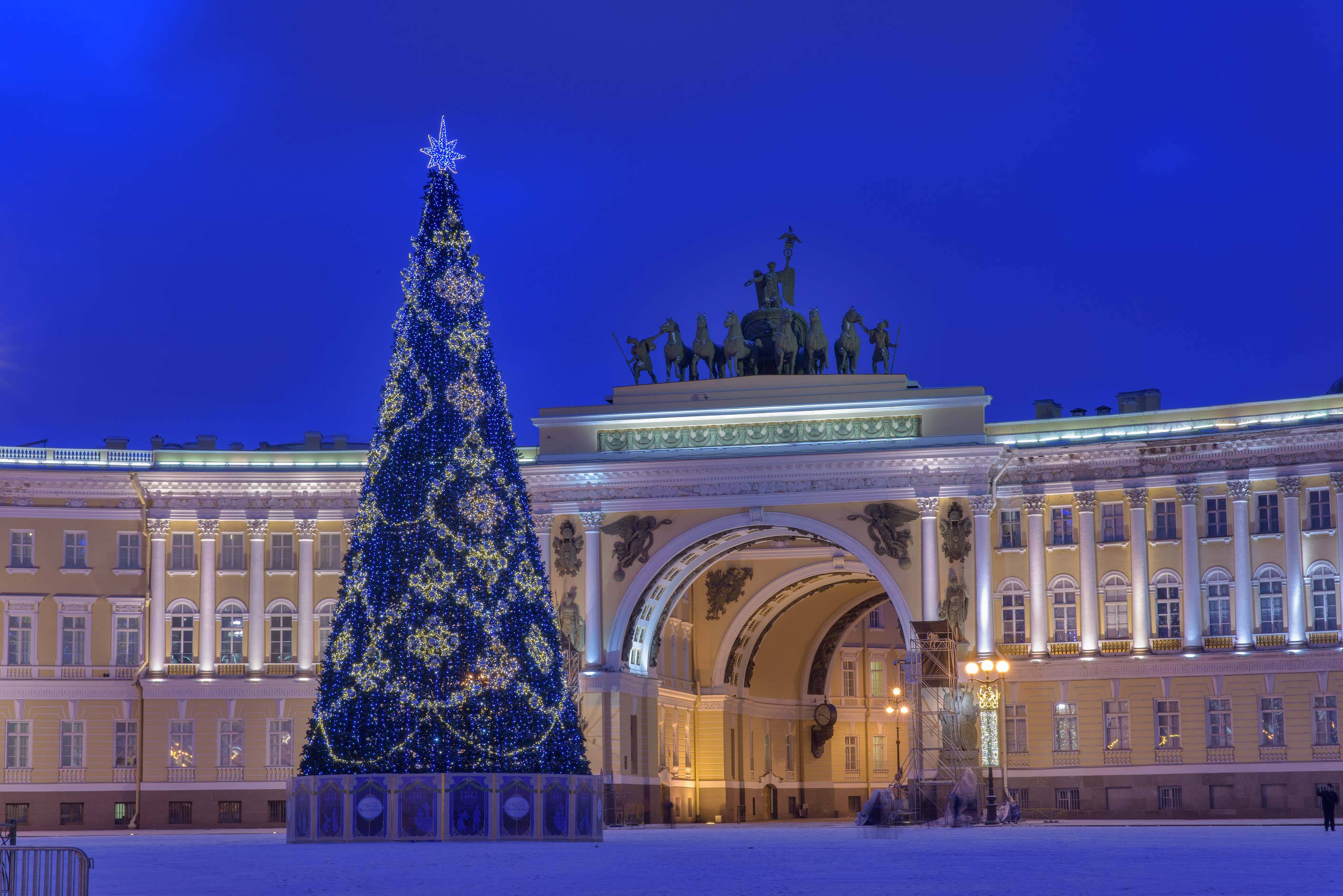 Kazan 桌布 壁紙 — 在深沉的暮色天空下，一座高聳的藍色聖誕樹矗立在宏偉的燈光宮殿前。