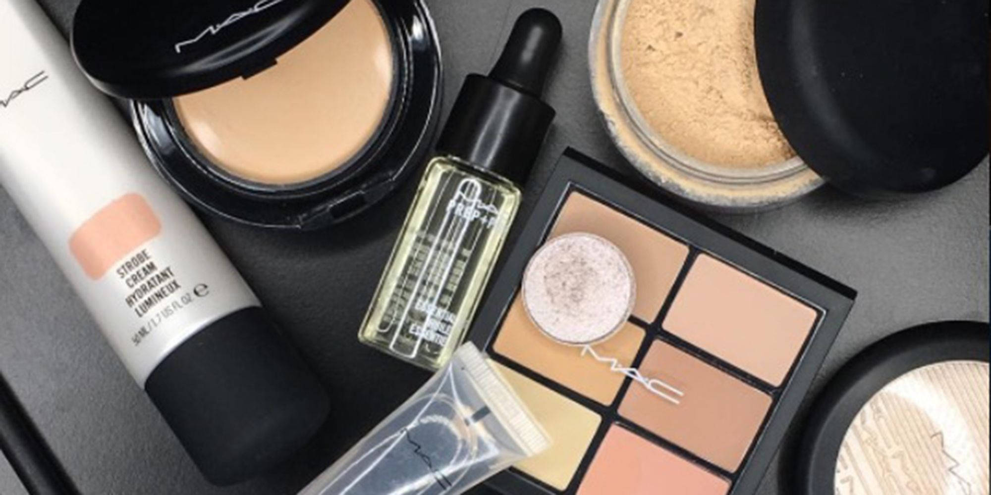 Cosmetics 桌布 壁紙 — 在深灰色表面上平鋪擺放的MAC化妝品，包括粉底、遮瑕膏、精華液和眼影盤。