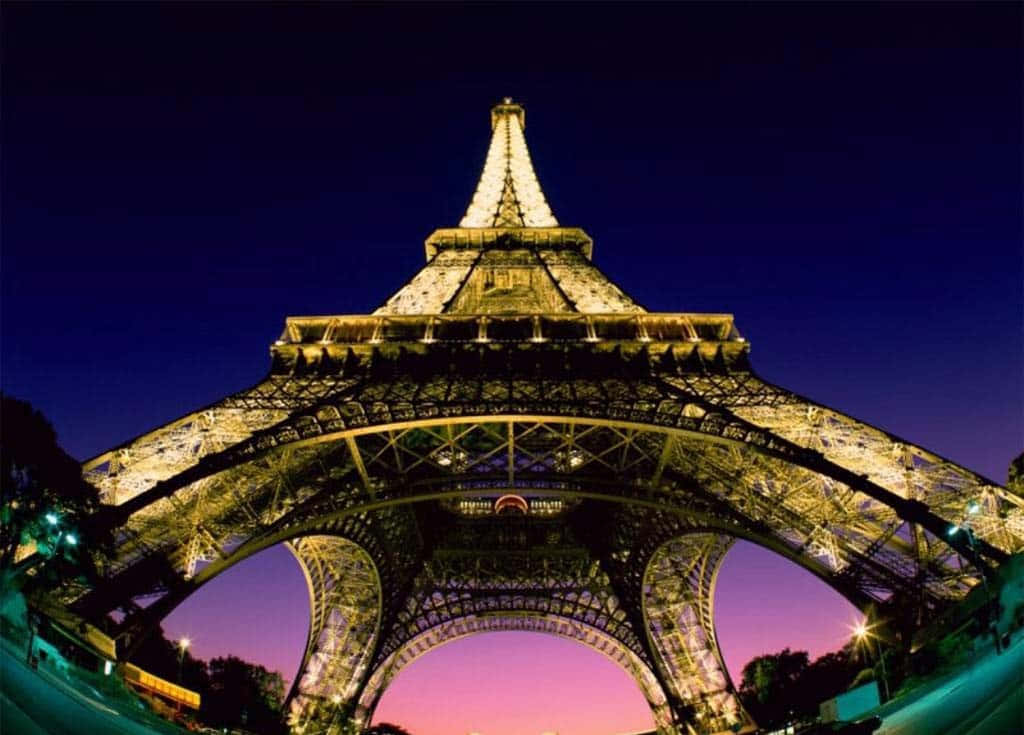 Eiffel Tower 桌布 壁紙 — 在深紫色和藍色天空的映襯下，艾菲爾鐵塔在黃昏時分被溫暖的燈光照亮。