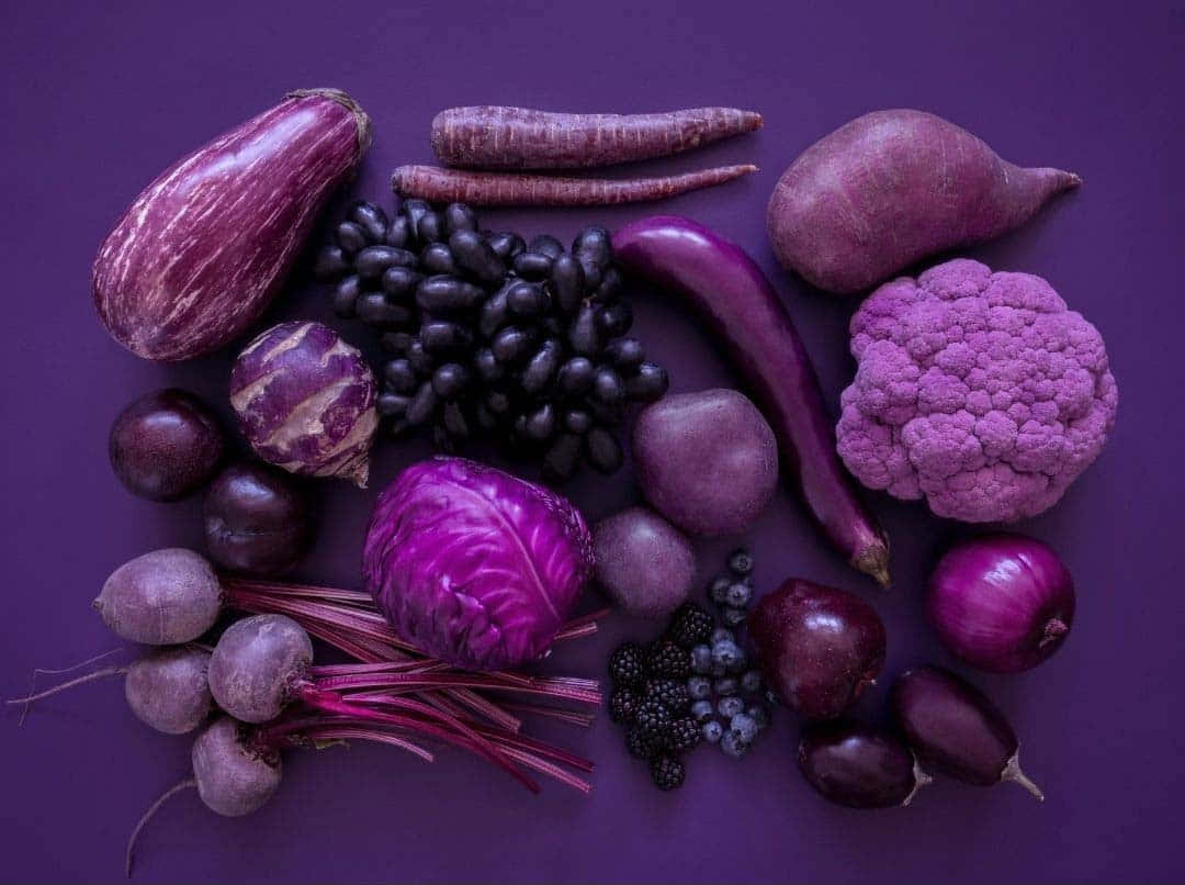 Fruits 桌布 壁紙 — 在深紫色背景上擺放充滿活力的紫色蔬菜和水果的平鋪佈局。