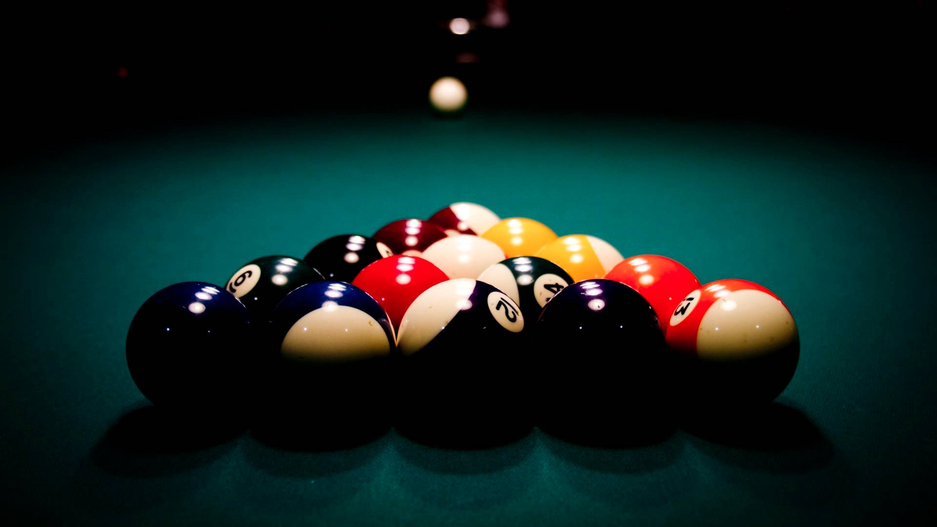 balls 桌布 壁紙 — 在深綠色絨布桌上，色彩繽紛的撞球排列成金字塔形，在戲劇性的聚光燈下。