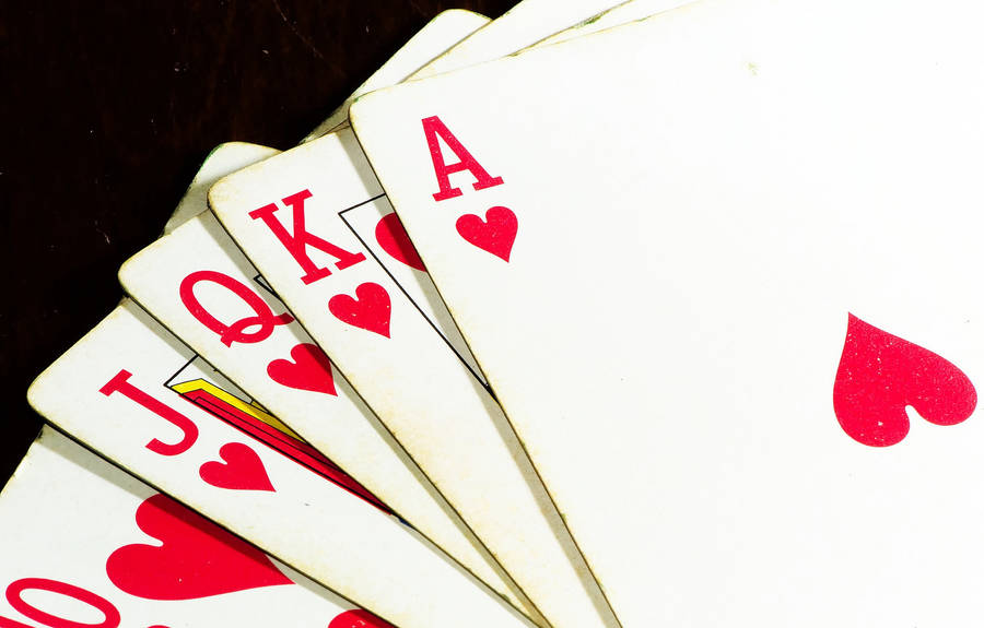 Poker 桌布 壁紙 — 在深色木質表面上，紅心撲克牌以扇形展開，顯示A、K、Q、J及10。