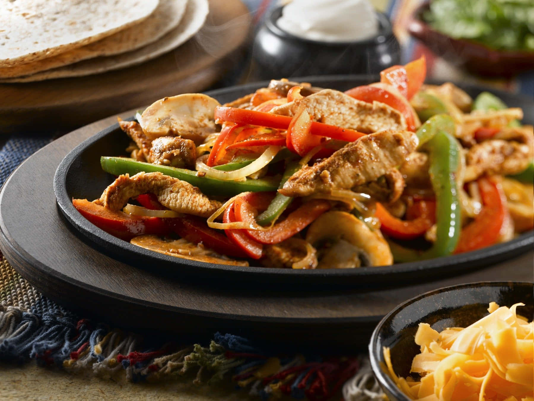 Mexican 桌布 壁紙 — 在深色盤子上，雞肉、青椒、洋蔥和蘑菇的鐵板法士達熱氣騰騰。