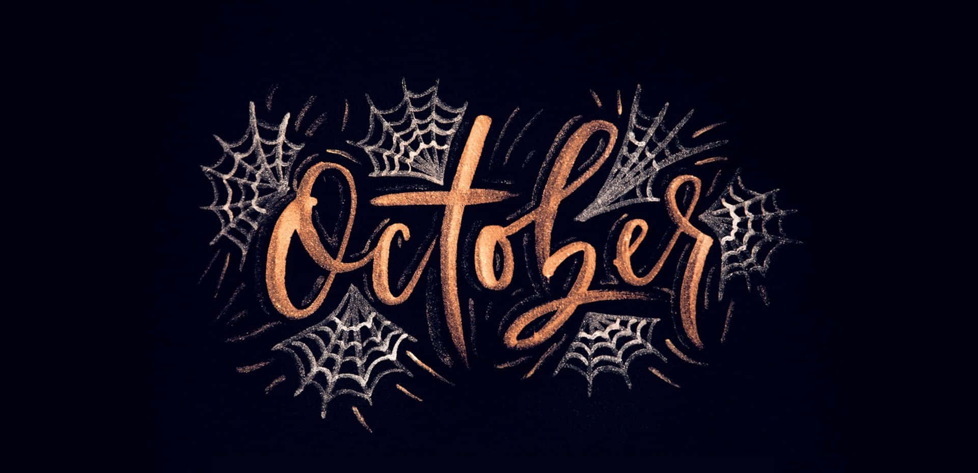 美學 桌布 壁紙 — 在深色背景上，以閃爍銅色字體書寫的「October」一詞，周圍環繞著銀色蜘蛛網。