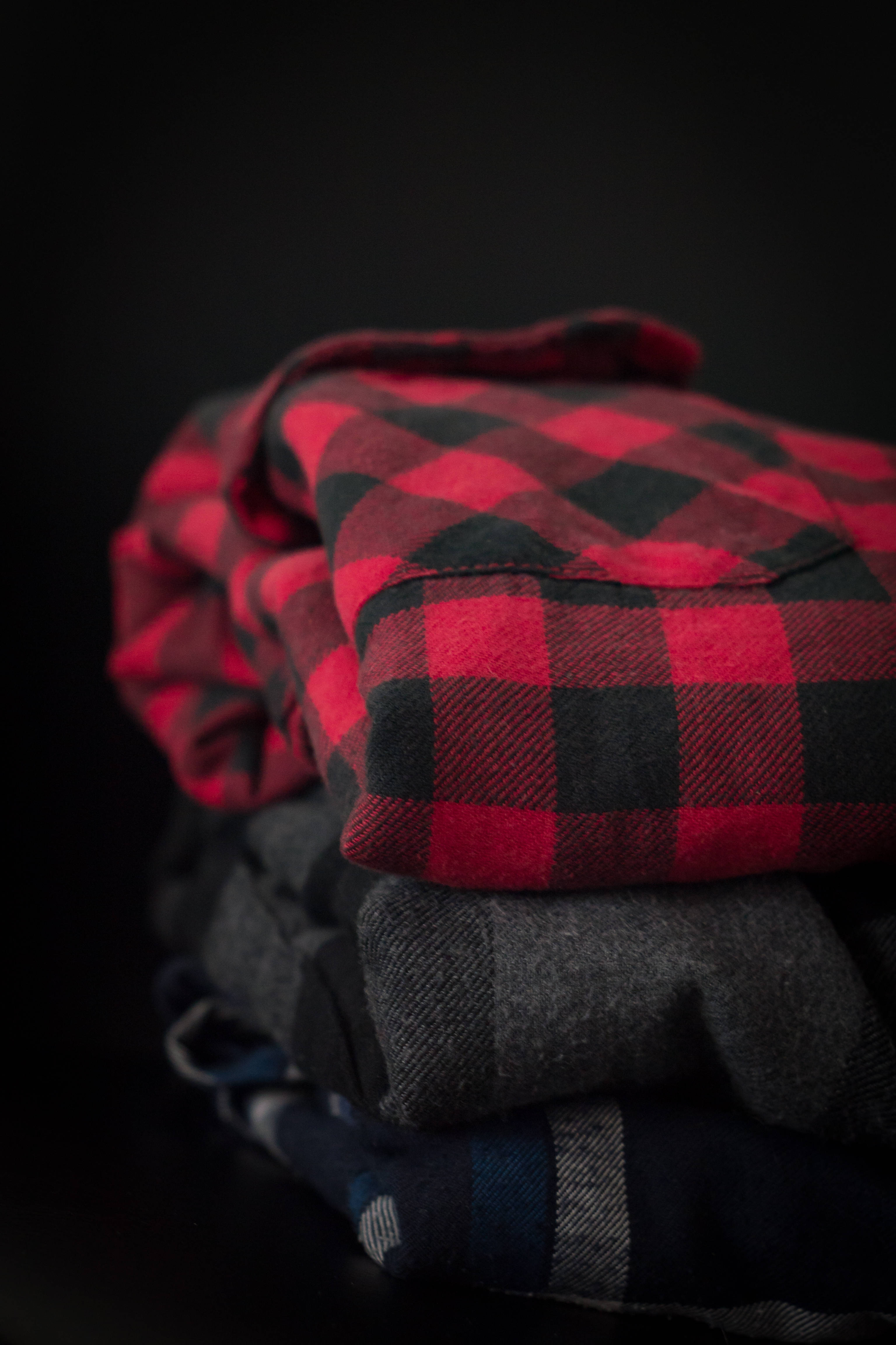 Checkered 桌布 壁紙 — 在深色背景上堆疊的紅色、黑色和灰色格子法蘭絨襯衫。