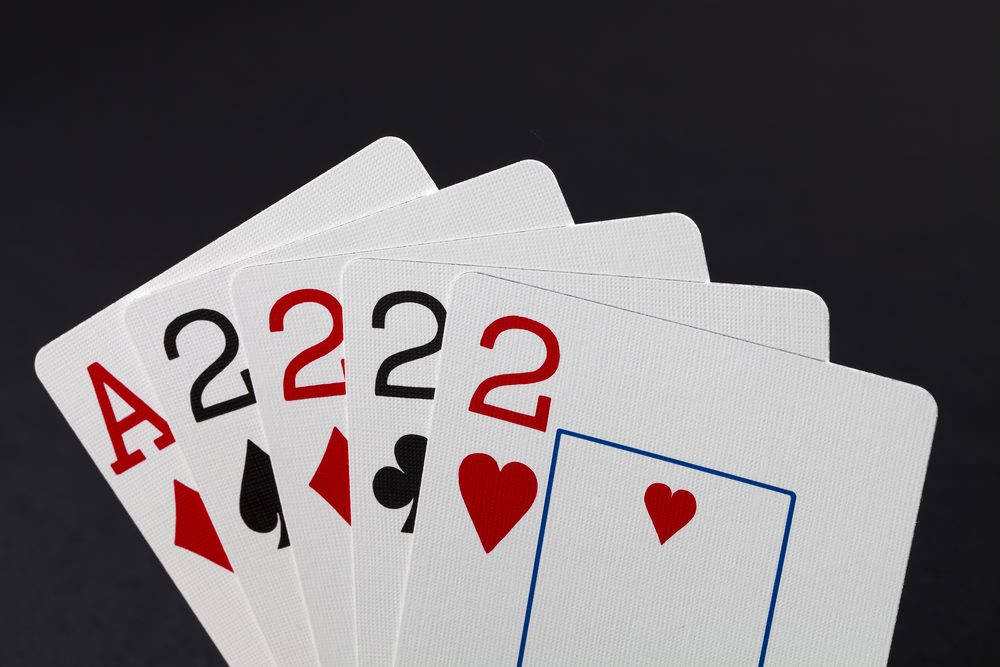 Playing Cards 桌布 壁紙 — 在深色背景上展開成扇形的撲克牌，顯示方塊A和四張2。