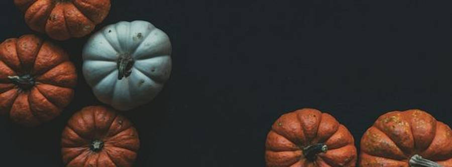 Facebook Cover 桌布 壁紙 — 在深色背景上排列橙色和淺藍色南瓜的平鋪構圖，留有充足負空間。