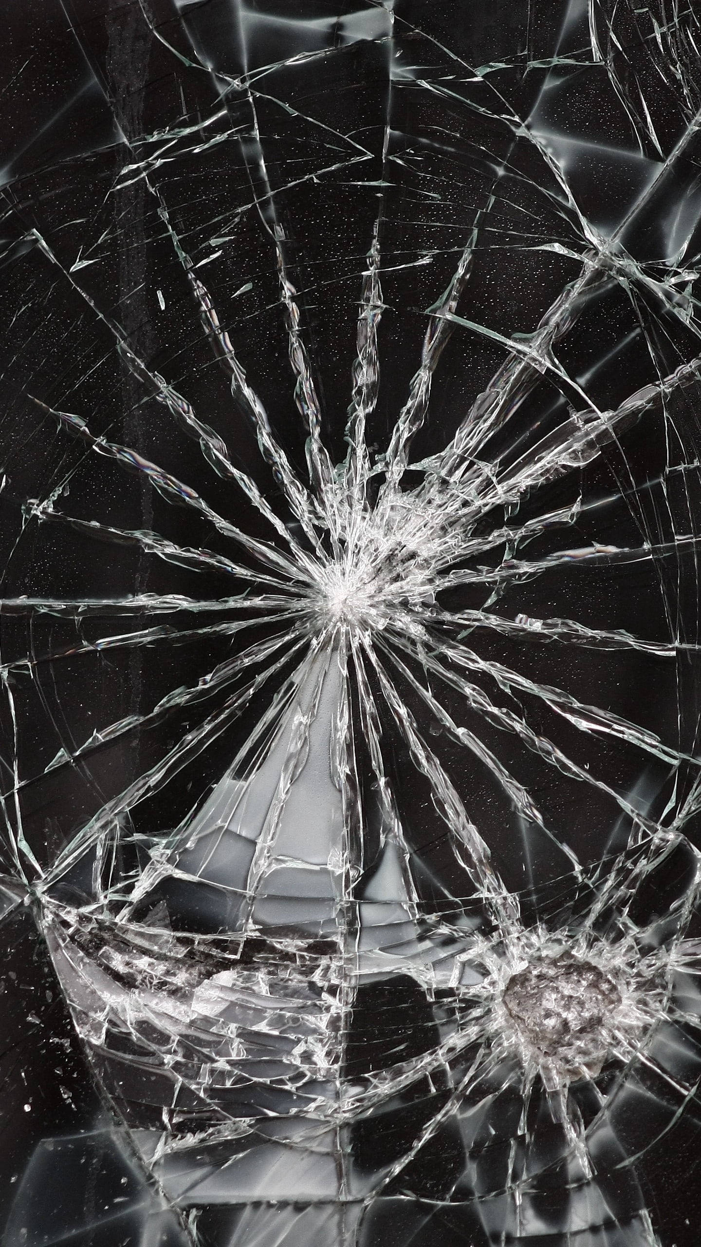 Broken Glass 桌布 壁紙 — 在深色背景下，一塊破碎的玻璃表面，從中央撞擊點散發出複雜的裂紋。