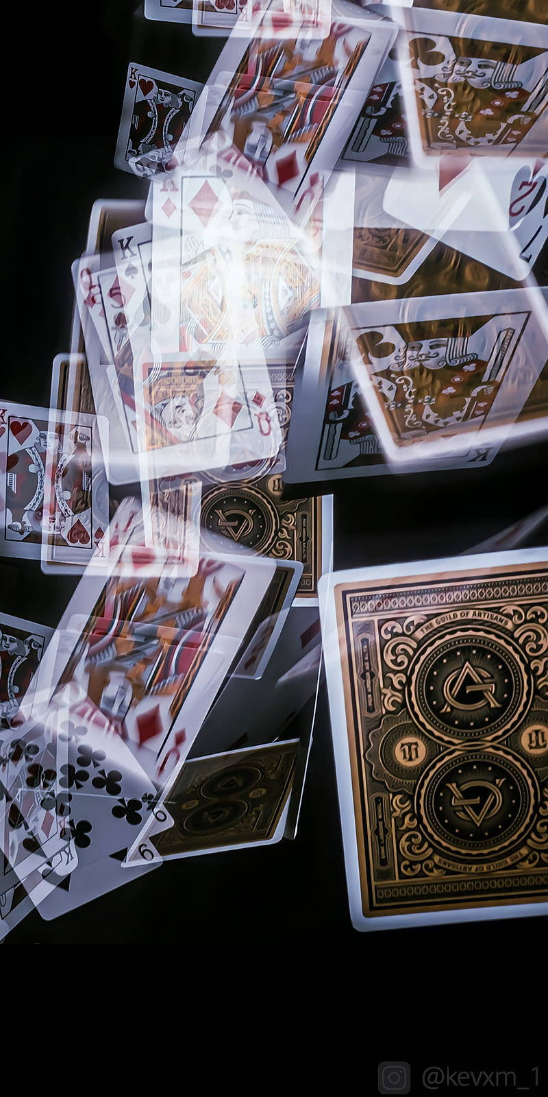Casino 桌布 壁紙 — 在深色背景下，帶有華麗金色背面和發光邊緣的墜落撲克牌。