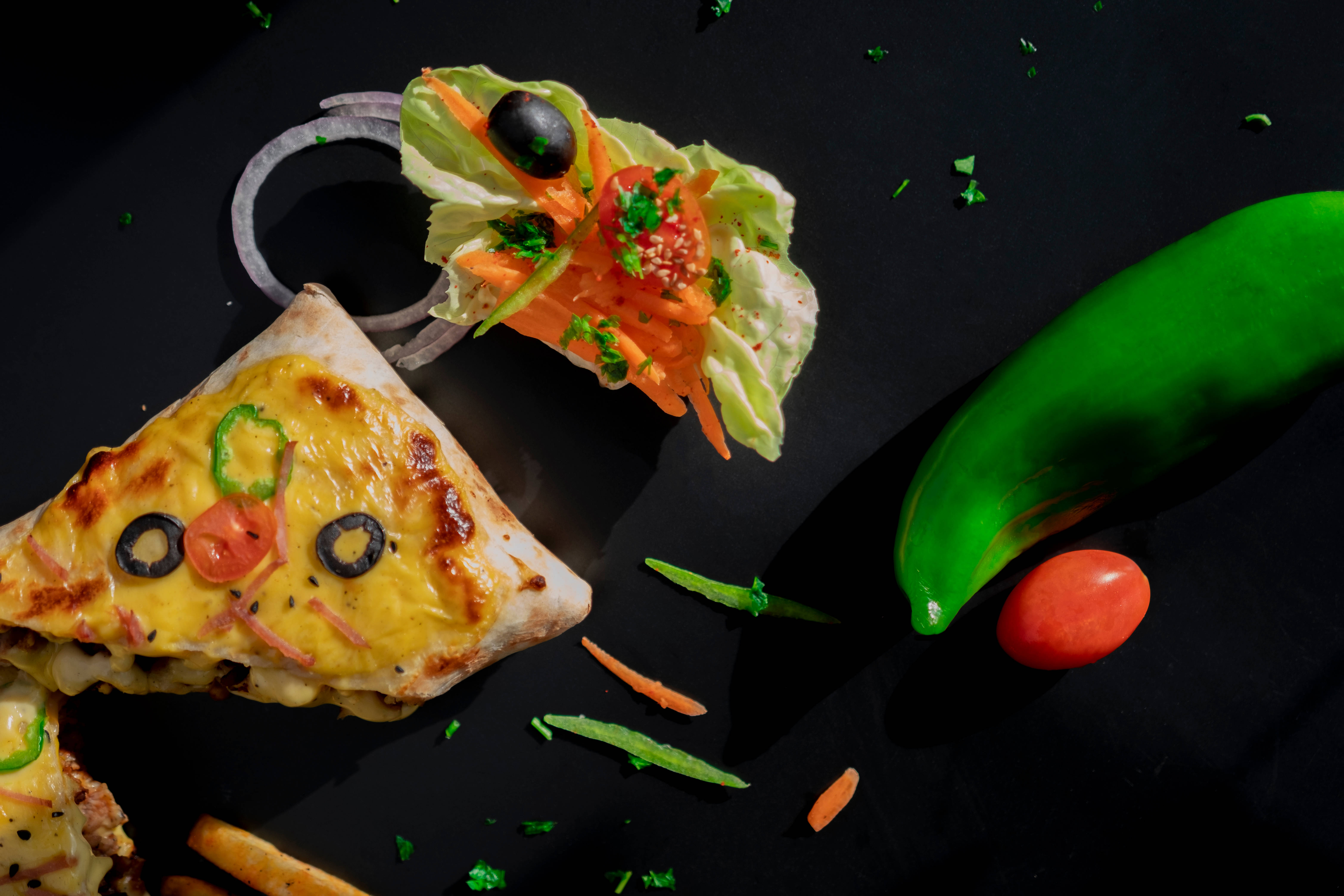 4K 食物 桌布 壁紙 — 在深色表面上，創意地擺放著一片披薩和沙拉，並以橄欖和蔬菜裝飾。