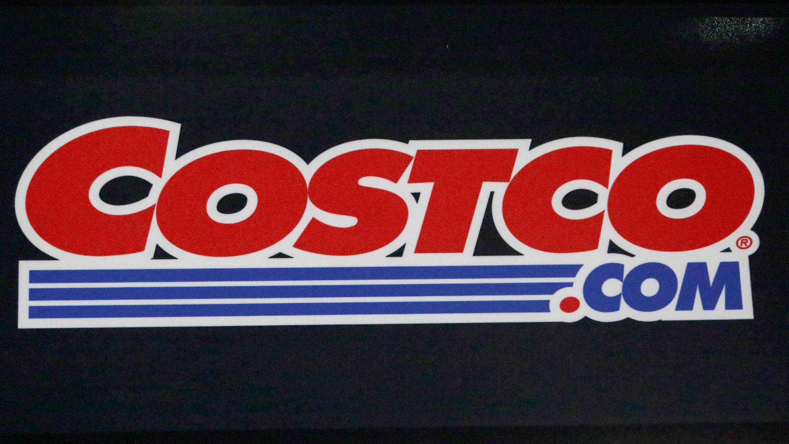 Costco 桌布 壁紙 — 在深色表面上的一個大膽的紅、白、藍 Costco.com 標誌貼紙。