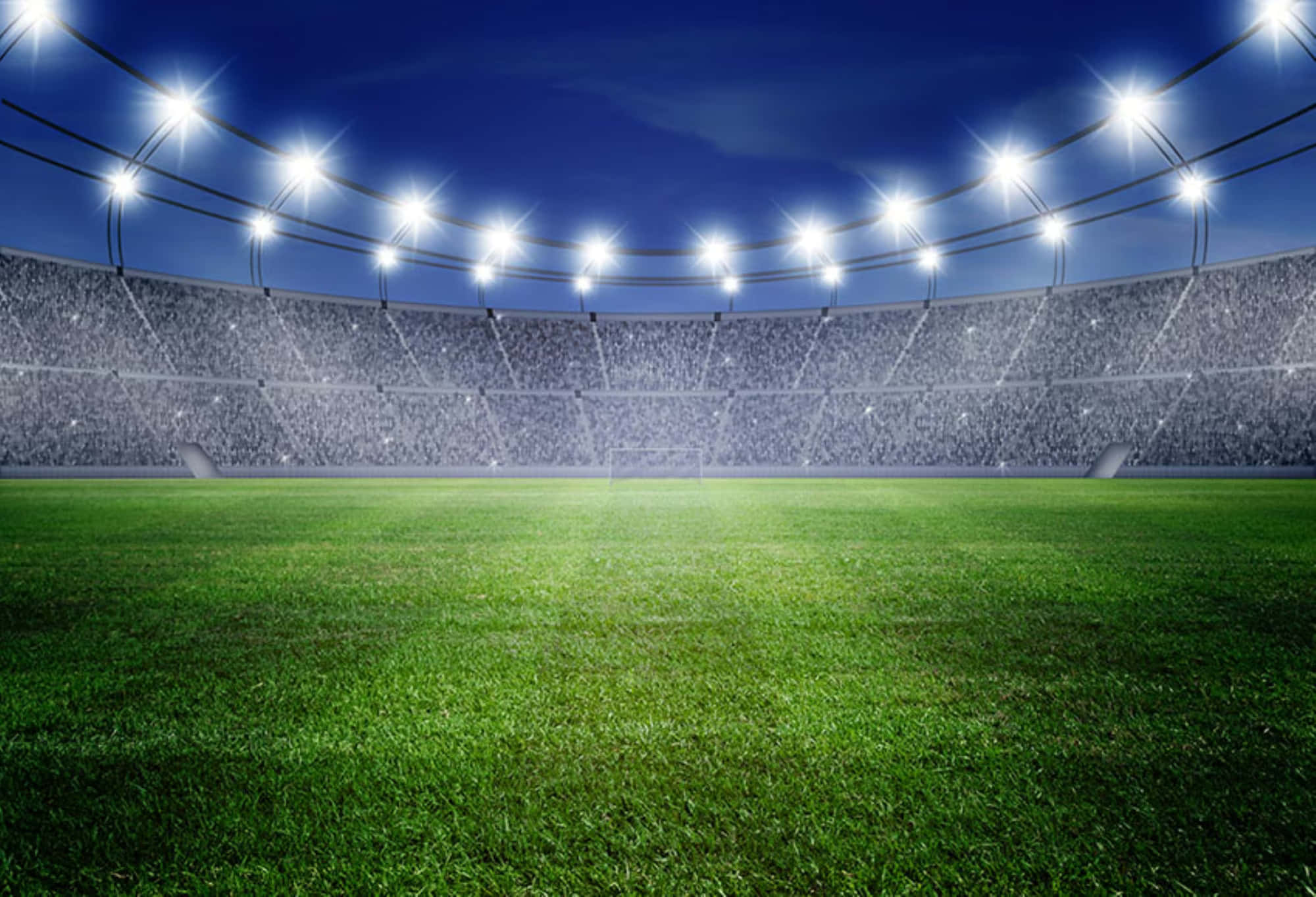 Stadium 桌布 壁紙 — 在深藍色夜空下，明亮的球場燈光照射著充滿活力的綠色足球場和擠滿觀眾的看台。