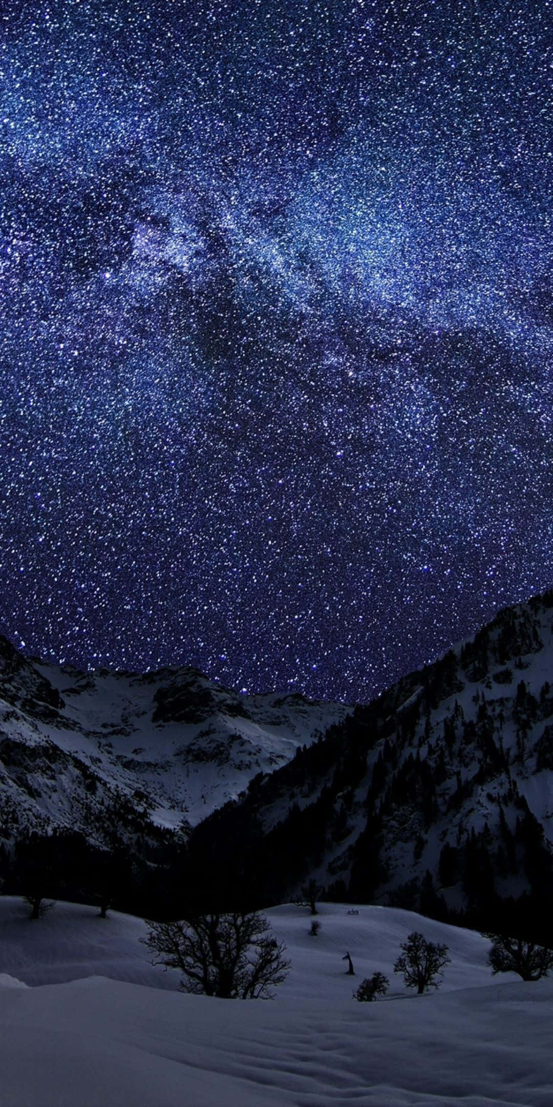 Winter 桌布 壁紙 — 在深藍色夜空下，銀河系橫跨積雪的山峰，景色令人嘆為觀止。