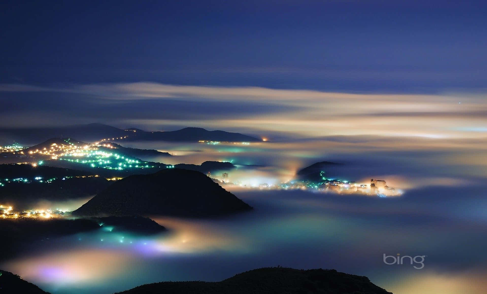 充滿霧氣和閃爍城市燈光的山谷夜景。 — 必應 壁紙