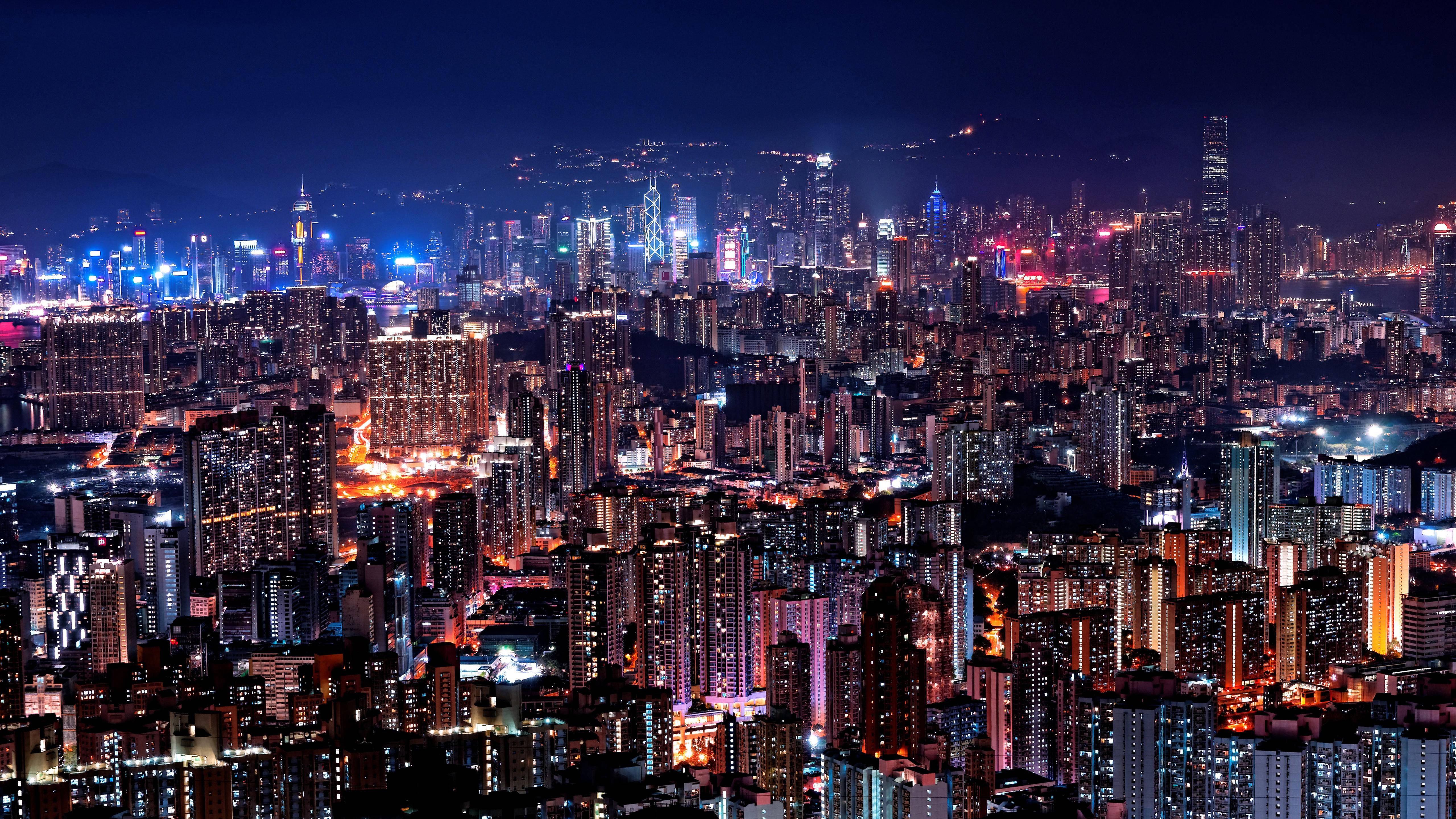 Skyscraper 桌布 壁紙 — 在深藍色天空下，高聳摩天大樓與閃爍街道構成的耀眼夜景城市景觀。