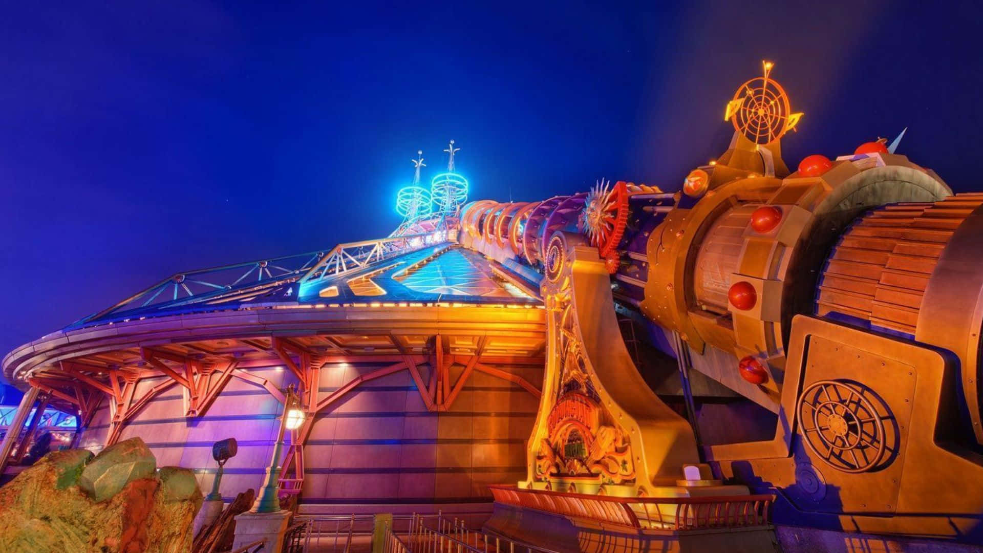 Disneyland 桌布 壁紙 — 在深藍色天空映襯下，閃爍著藍色和橙色光芒的充滿活力的夜間遊樂園遊樂設施。
