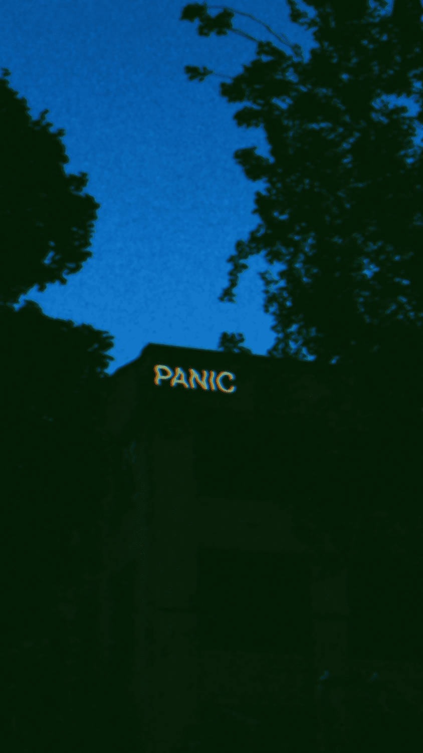 Panic 桌布 壁紙 — 在深藍色暮色天空下，樹影襯托的黑暗建築上發光的恐慌標誌。