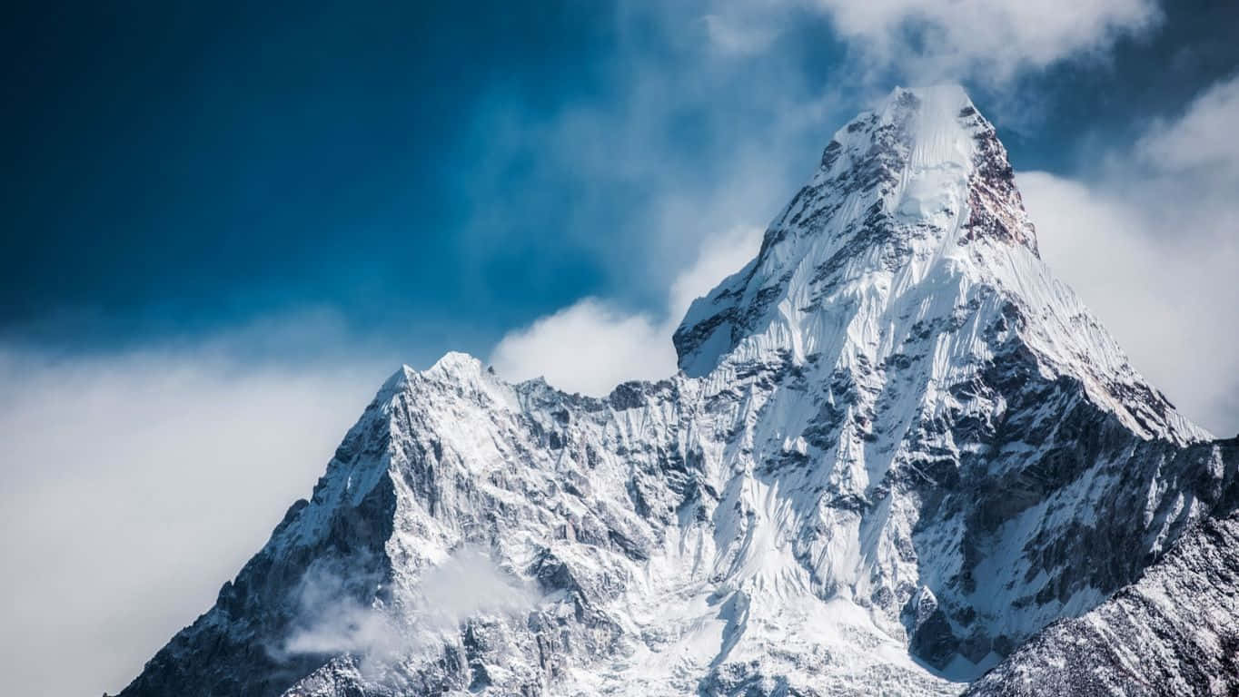 1364x768 桌布 壁紙 — 在深藍色的天空下，雄偉的雪山峰頂穿過旋轉的雲層。