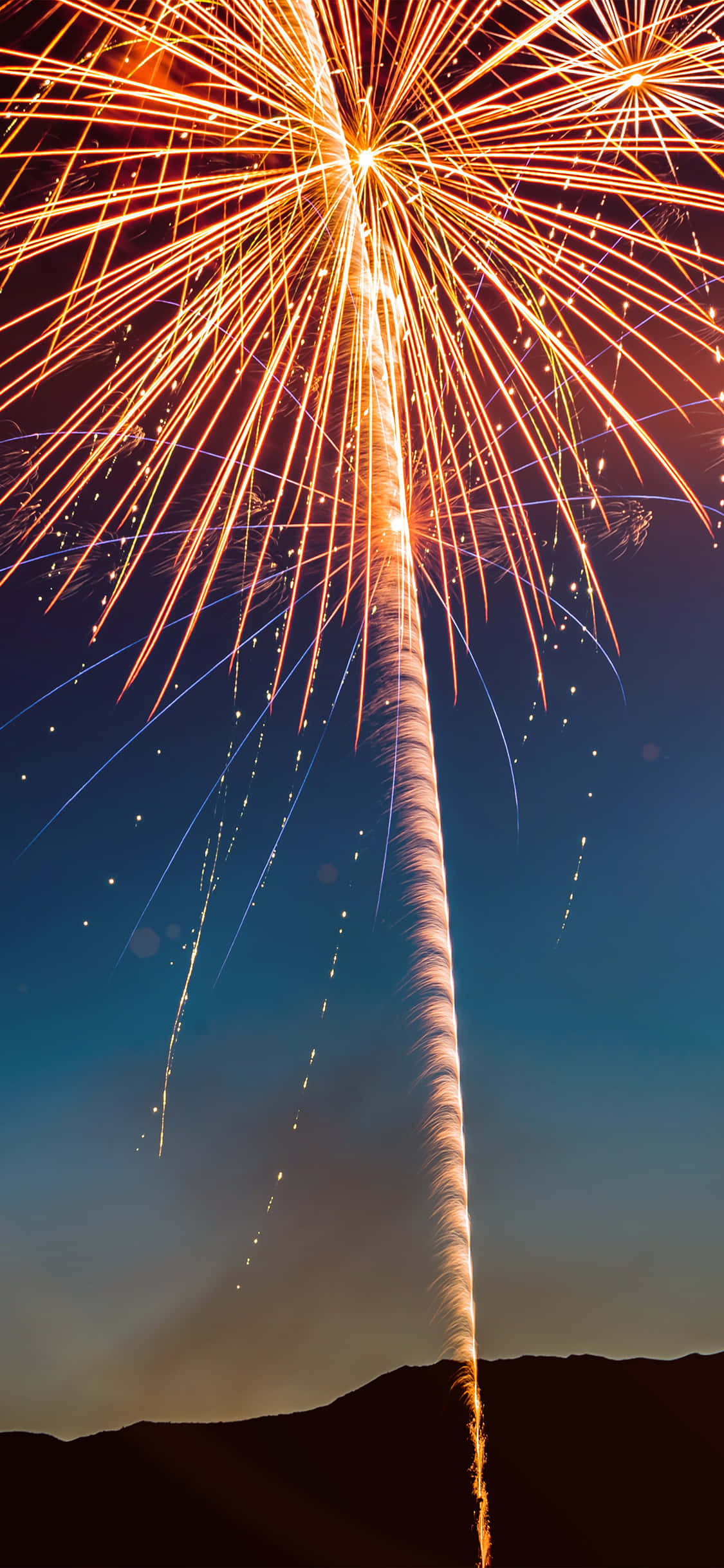 Fireworks 桌布 壁紙 — 在深藍色的暮色天空中，黑暗輪廓的山丘上方，絢麗的煙火爆炸。