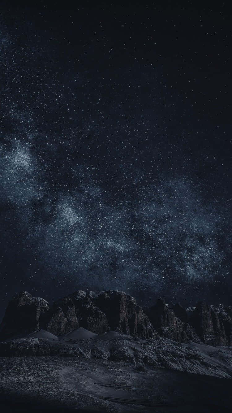 Astrology iPhone 桌布 壁紙 — 在深藍色調下，銀河拱跨黑暗鋸齒山脈的星空夜空。