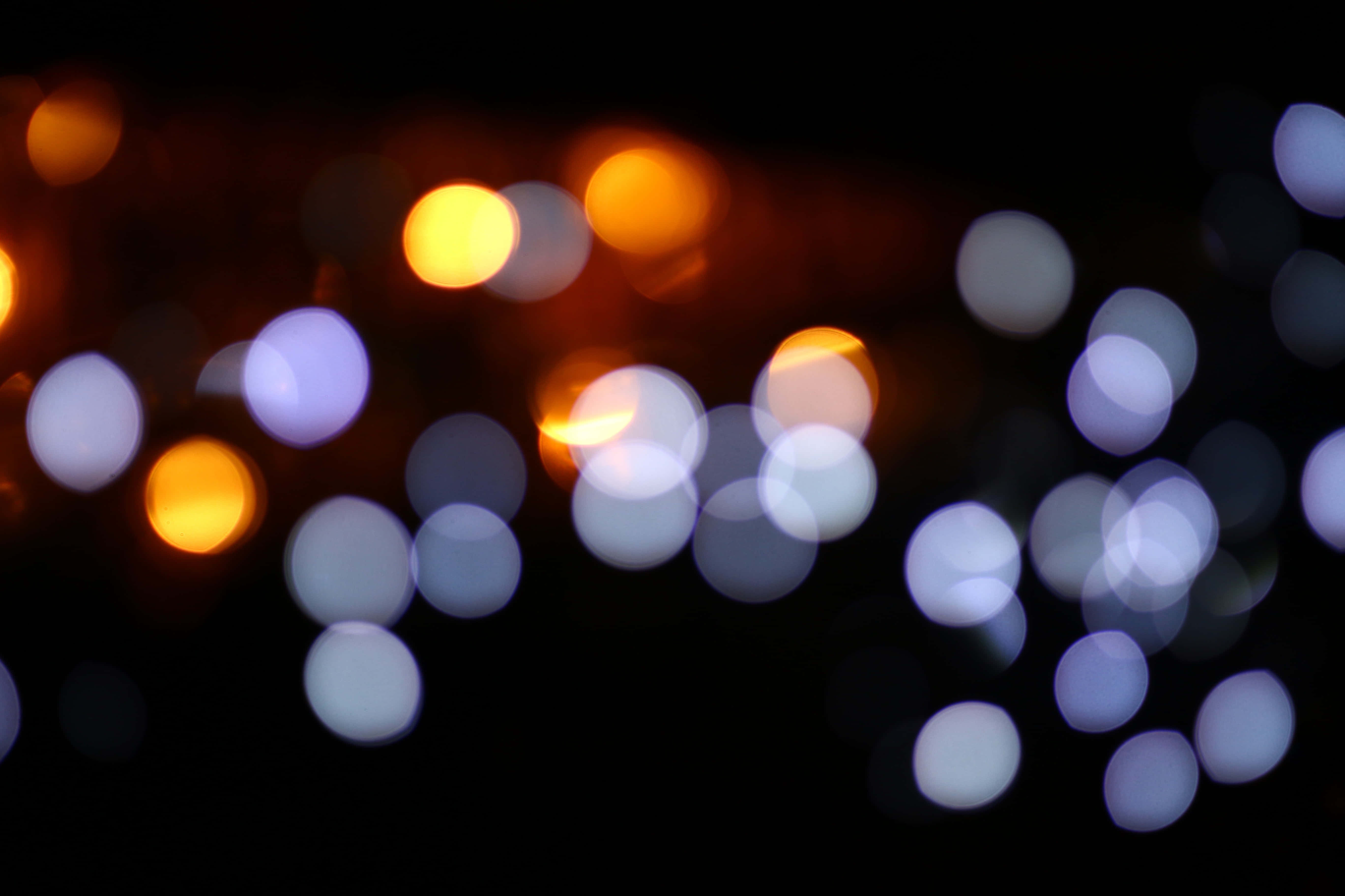 lights 桌布 壁紙 — 在深邃的黑色夜空背景下，發光的橙色和冷白色燈光營造出迷人的散景效果。