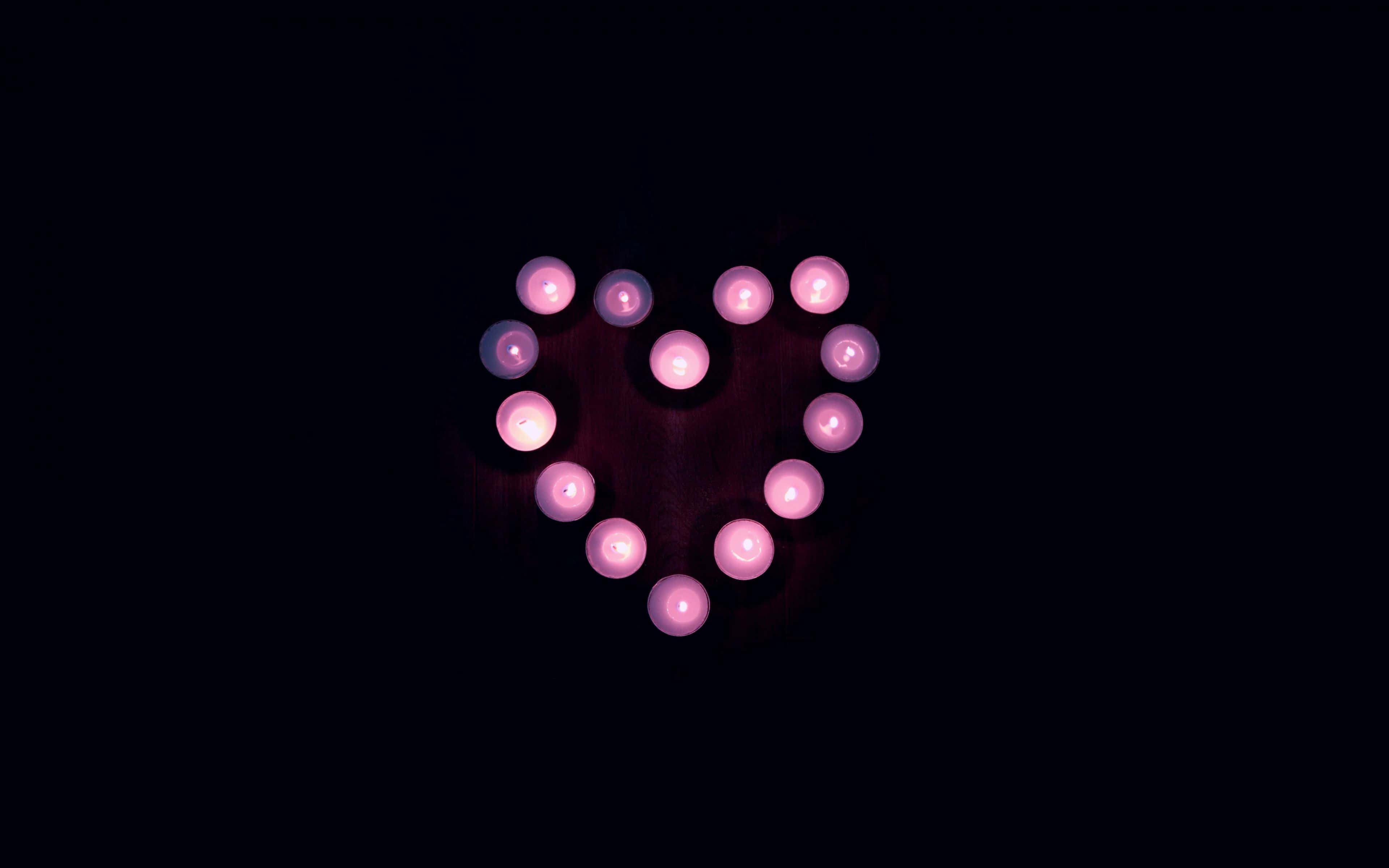 Dark Love 桌布 壁紙 — 在深黑色背景上，由發光的粉紅色蠟燭形成的愛心形狀。