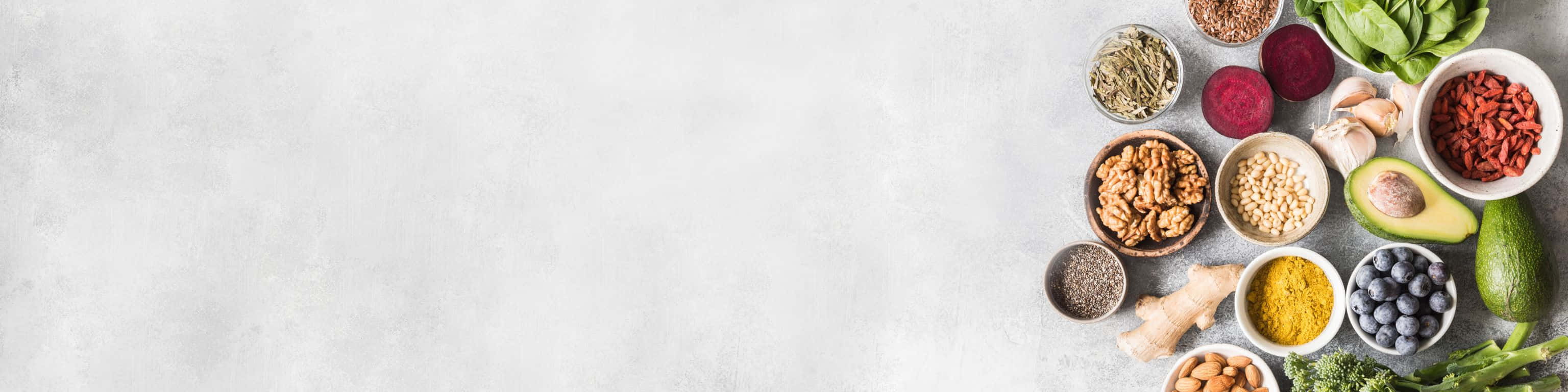 3072x768 桌布 壁紙 — 在淺灰色紋理表面上整齊排列的充滿活力的健康超級食物，如枸杞、核桃和酪梨的平鋪佈局。