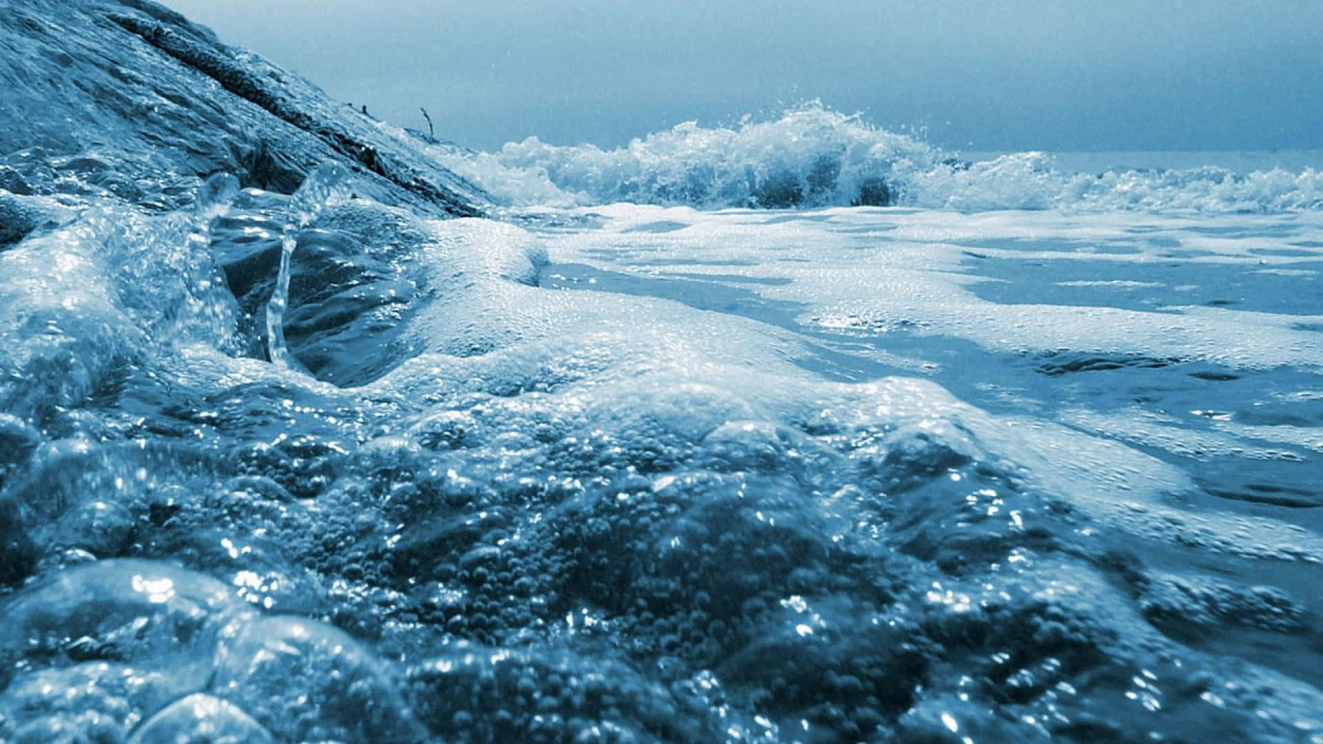 Ocean Waves 桌布 壁紙 — 在清涼的藍天下，泡沫海浪拍打冰岩的特寫。